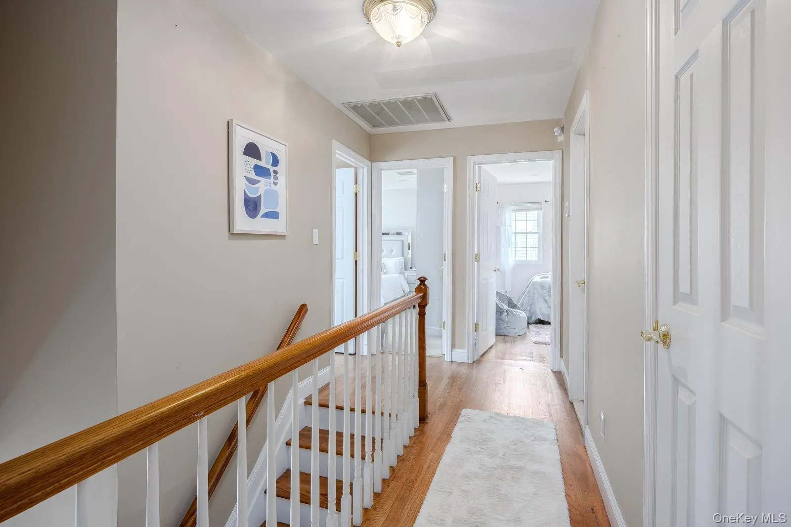 Hardwood flooring throughout the hallway and staircase, featuring white risers and a wood-finish handrail Hardwood flooring throughout the hallway and staircase, featuring white risers and a wood-finish handrail