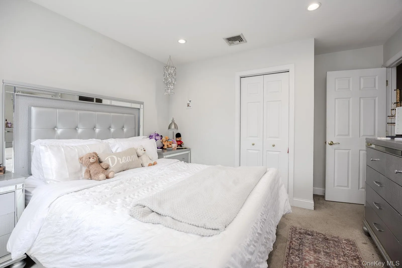 Recessed lighting, white bi-fold closet doors, white paneled door, and neutral-toned carpeting Recessed lighting, white bi-fold closet doors, white paneled door, and neutral-toned carpeting