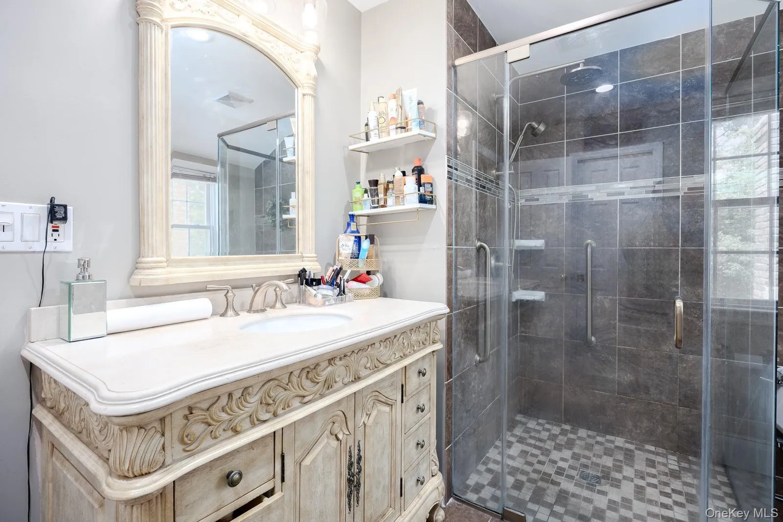 Vanity with an integrated sink, a large framed mirror, and a glass-enclosed shower with tile surround Vanity with an integrated sink, a large framed mirror, and a glass-enclosed shower with tile surround