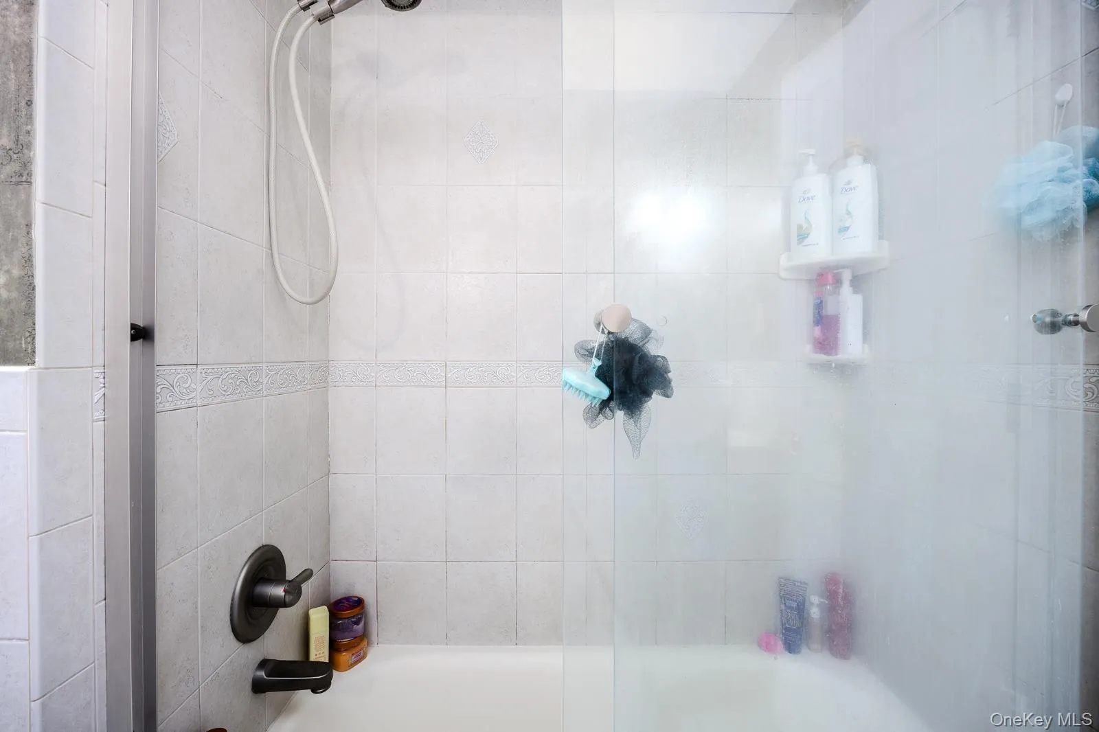 Tub-shower combination featuring white tile surround with brushed nickel fixtures Tub-shower combination featuring white tile surround with brushed nickel fixtures