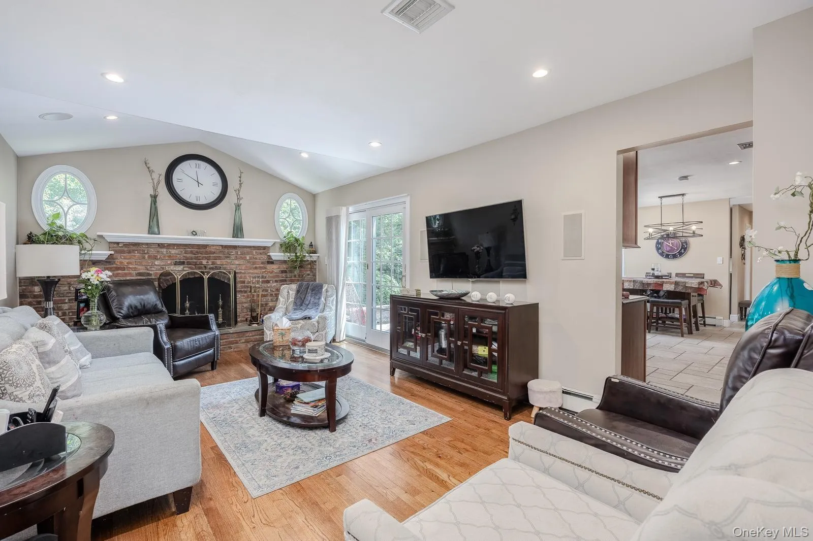 Vaulted ceiling, recessed lighting, brick-clad fireplace, wood-finish flooring, and French doors leading to exterior Vaulted ceiling, recessed lighting, brick-clad fireplace, wood-finish flooring, and French doors leading to exterior