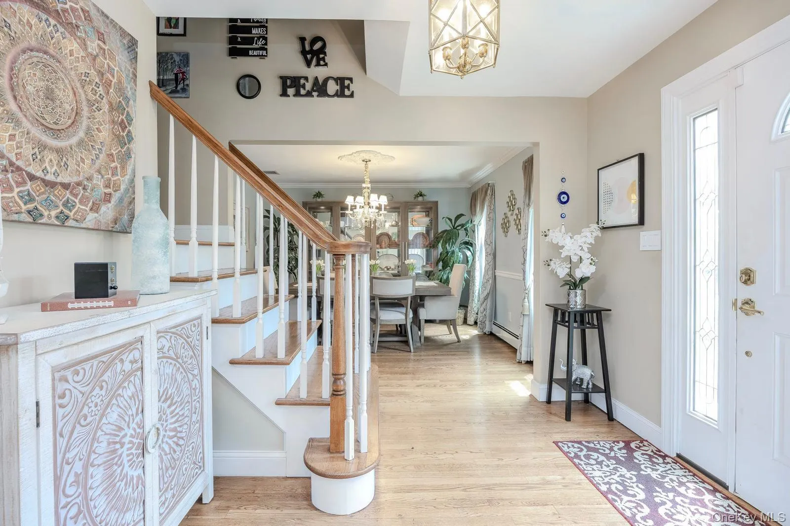 Hardwood flooring throughout, white painted staircase with wood handrail, traditional chandelier lighting, and a white entry door with decorative glass inserts Hardwood flooring throughout, white painted staircase with wood handrail, traditional chandelier lighting, and a white entry door with decorative glass inserts