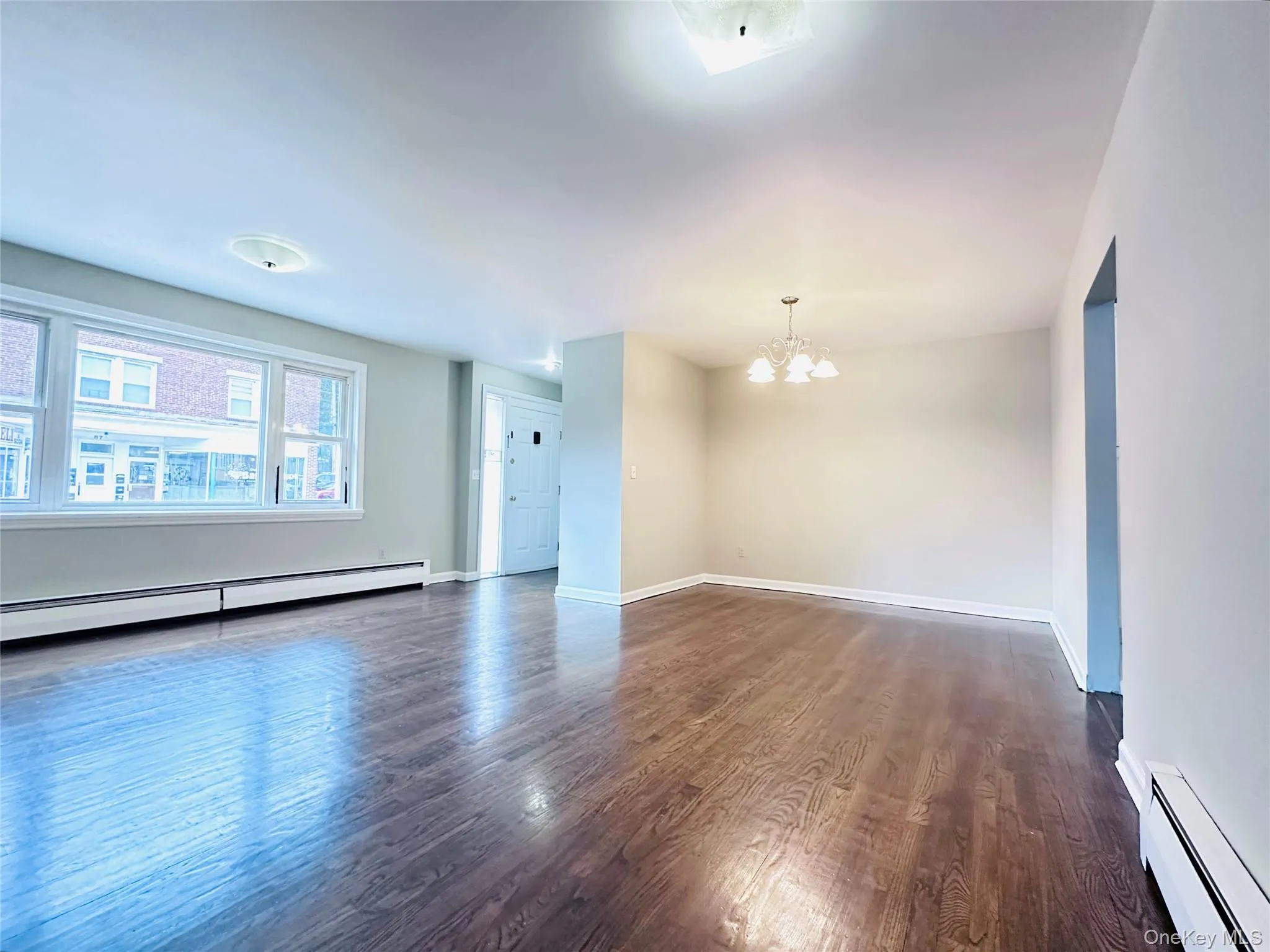 Spacious room featuring wood-finish flooring and a chandelier Spacious room featuring wood-finish flooring and a chandelier