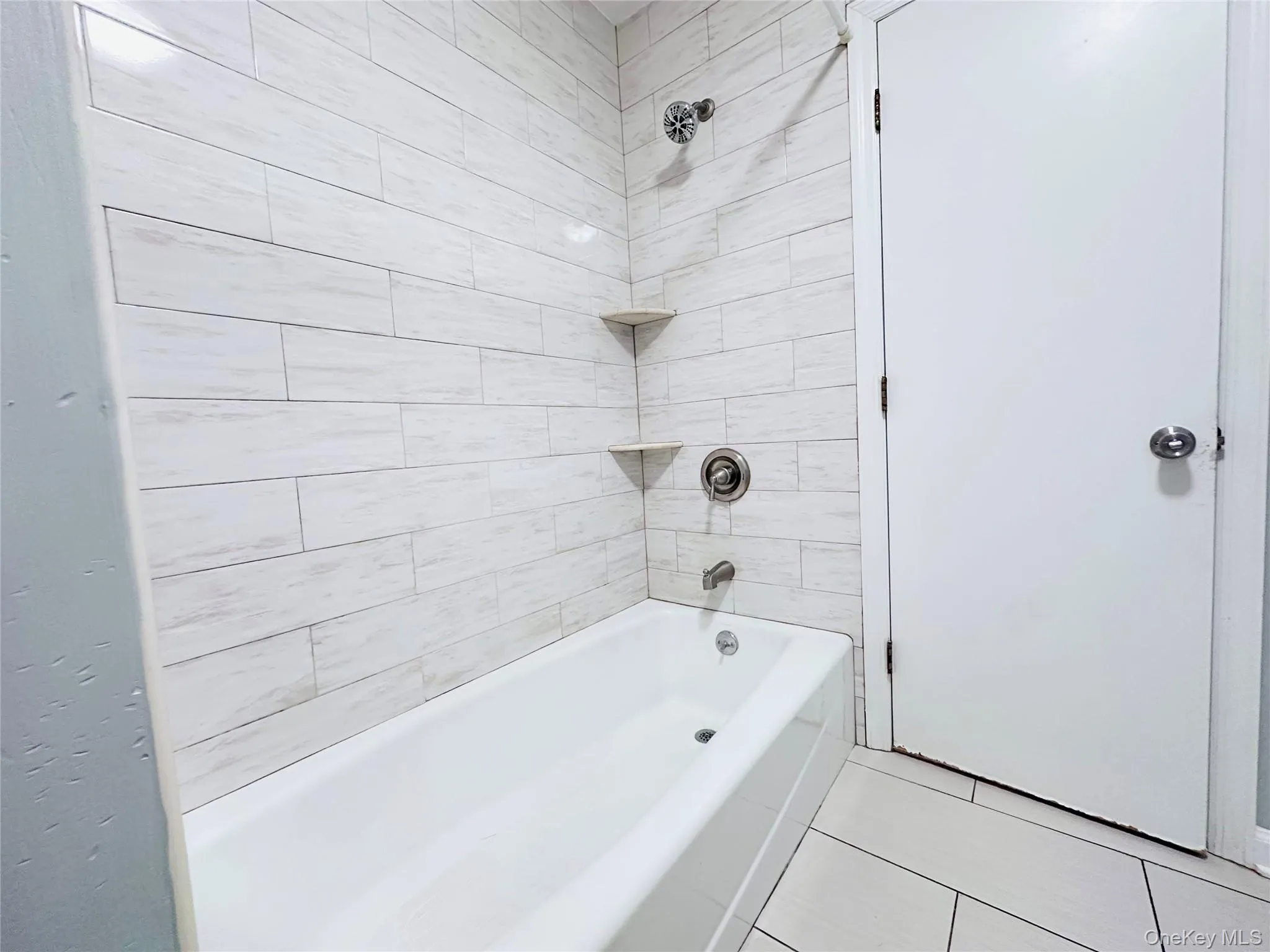 tile surround with integrated corner shelves and a chrome shower fixture tile surround with integrated corner shelves and a chrome shower fixture
