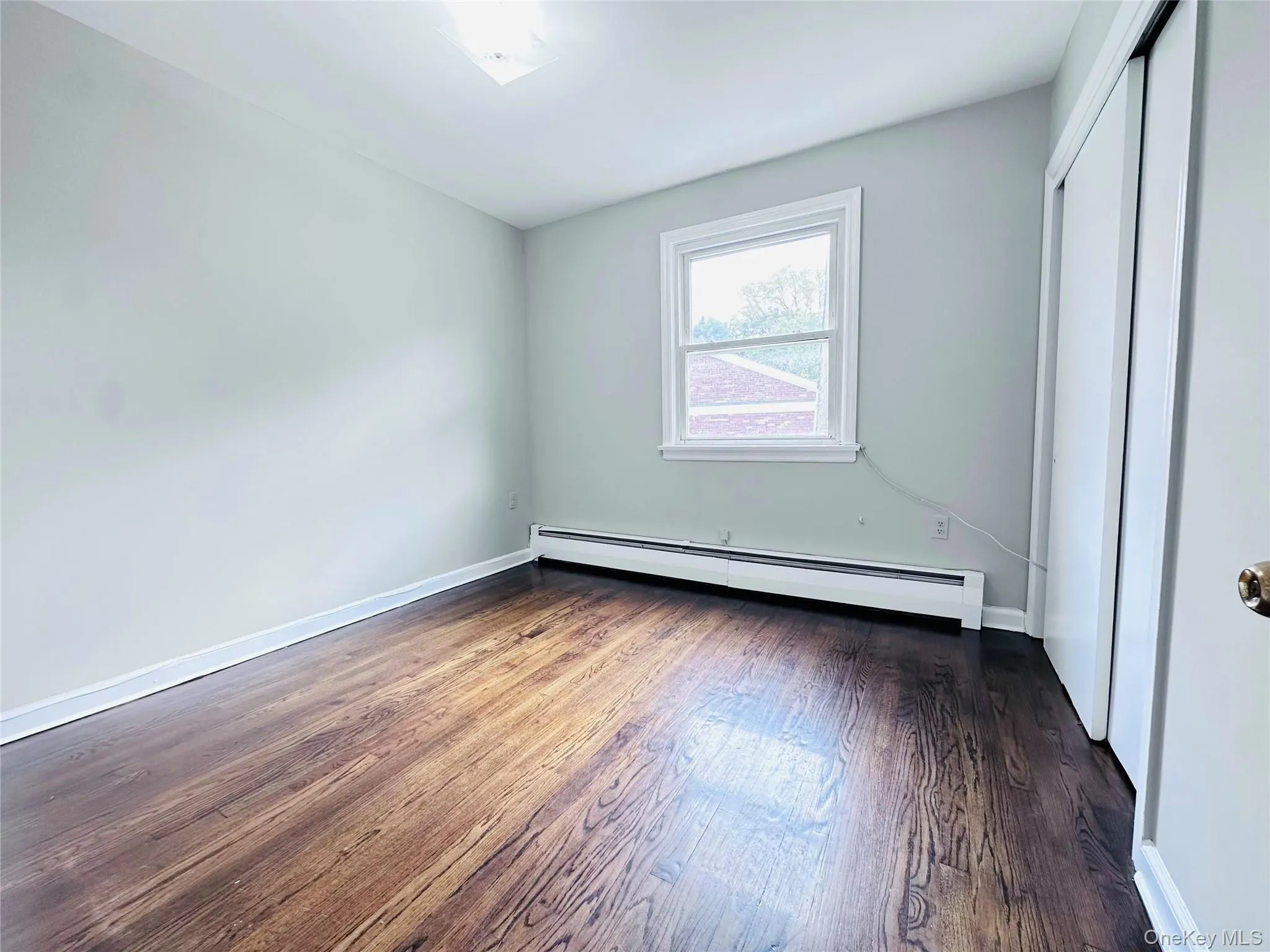 Bedroom 2 featuring wood-finish flooring, natural light, ceiling light fixture and a built-in closet with sliding doors Bedroom 2 featuring wood-finish flooring, natural light, ceiling light fixture and a built-in closet with sliding doors