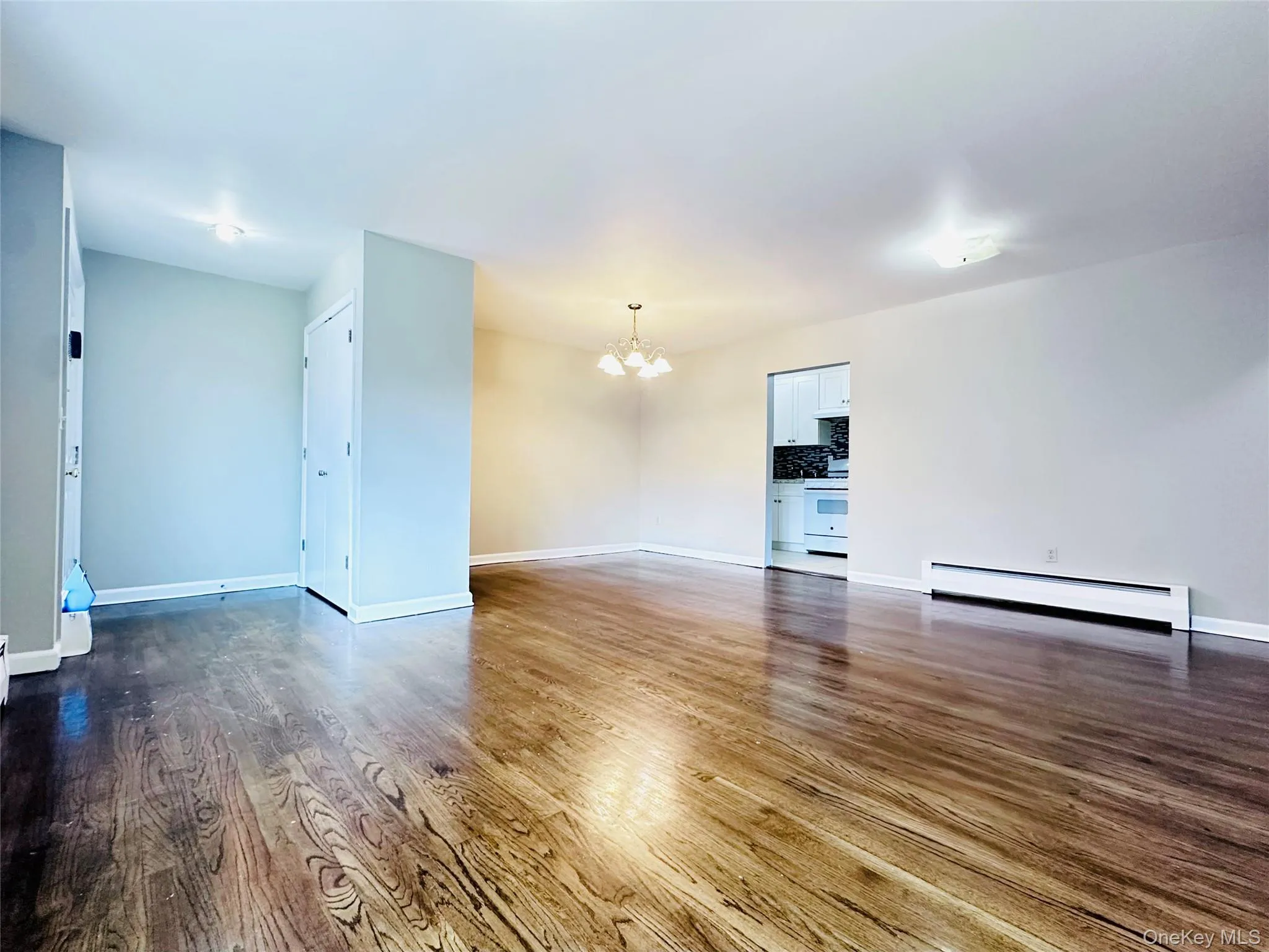 Open-concept living space featuring wood-finish flooring, recessed lighting, and baseboard heating system Open-concept living space featuring wood-finish flooring, recessed lighting, and baseboard heating system