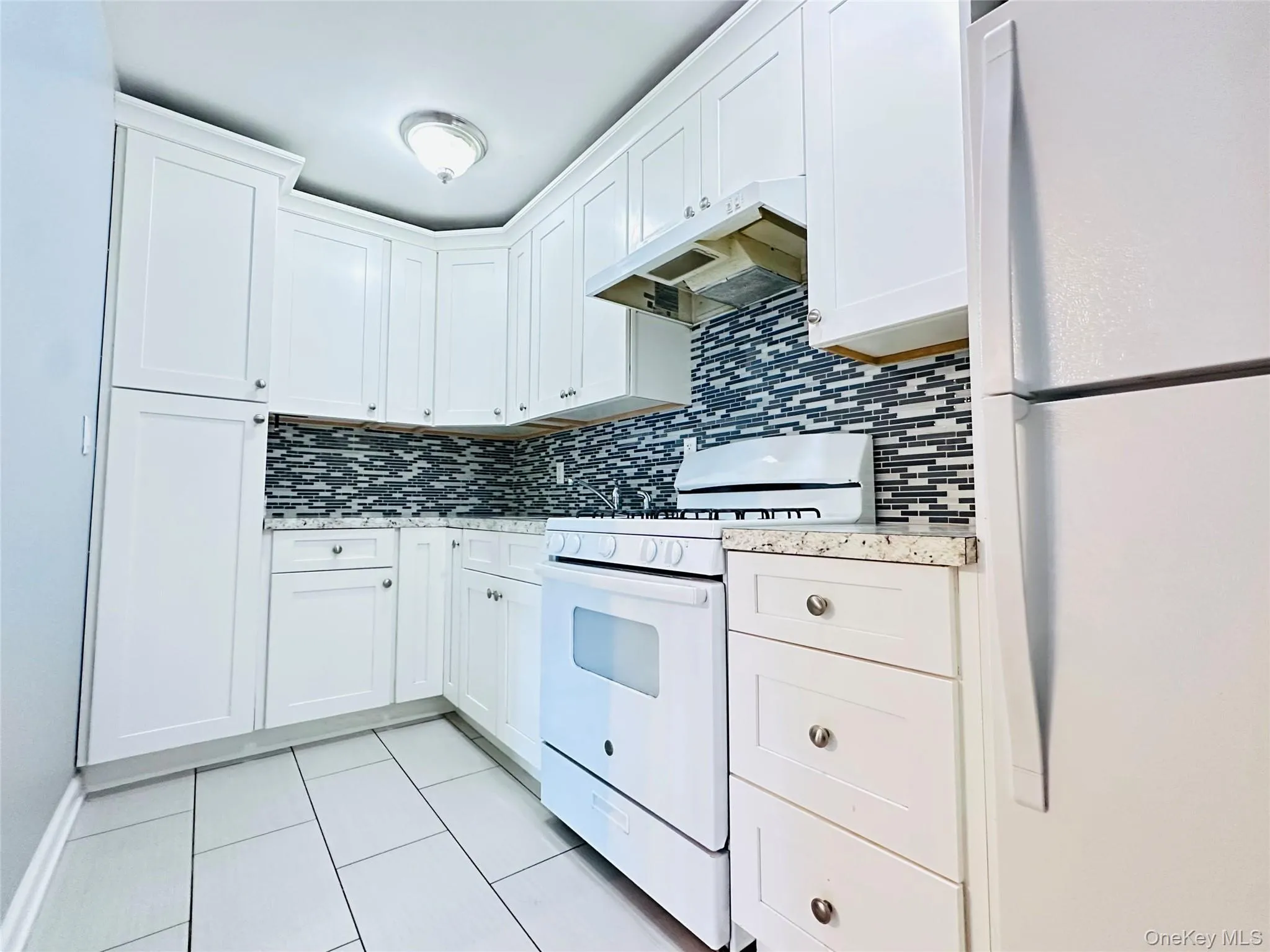 Stainless steel appliances, gas range, spacious fridge, and white tile flooring Stainless steel appliances, gas range, spacious fridge, and white tile flooring