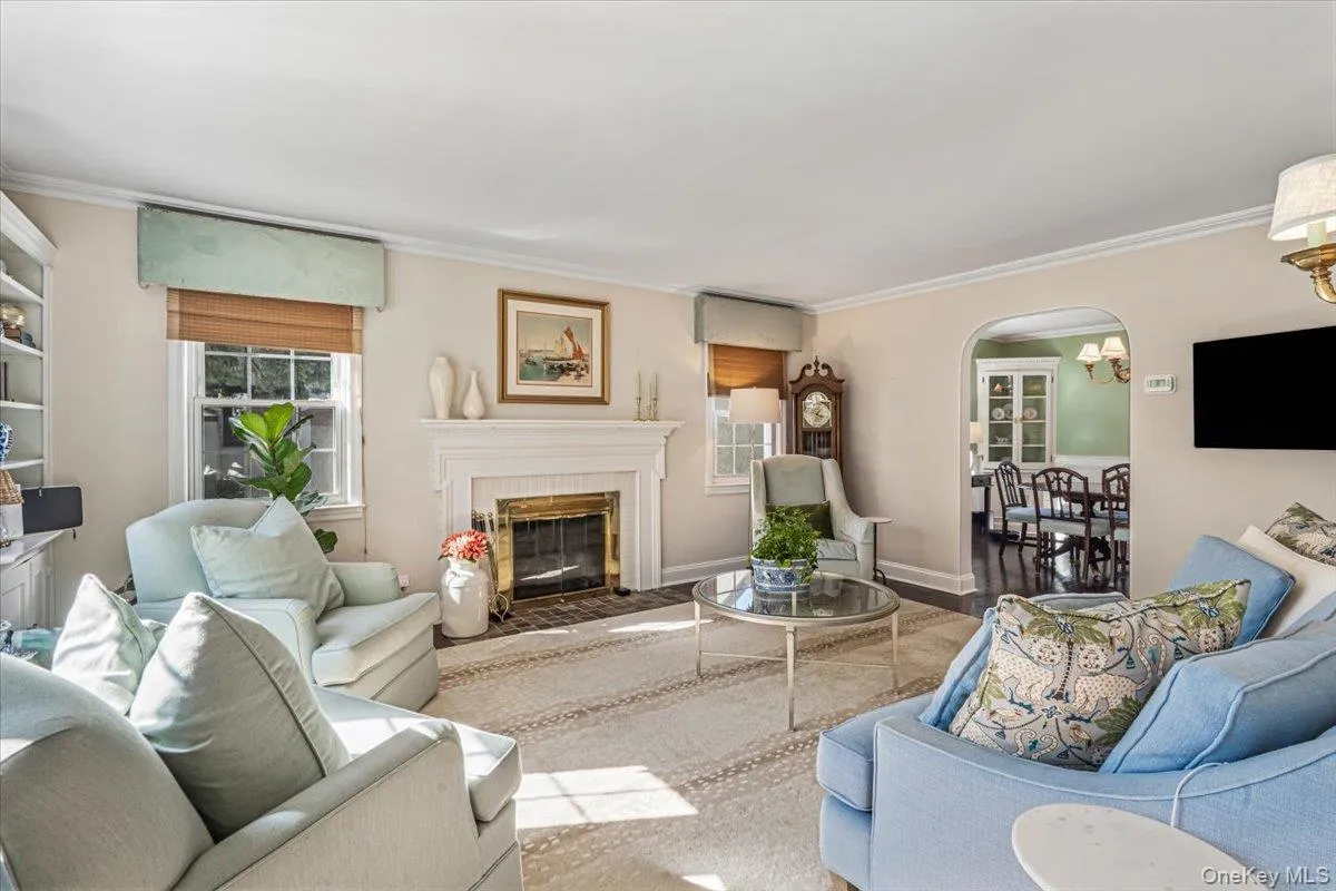 Living area featuring a classic fireplace ( Gas ) with a brass firebox, built-in shelving, crown molding, and an arched doorway Living area featuring a classic fireplace ( Gas ) with a brass firebox, built-in shelving, crown molding, and an arched doorway