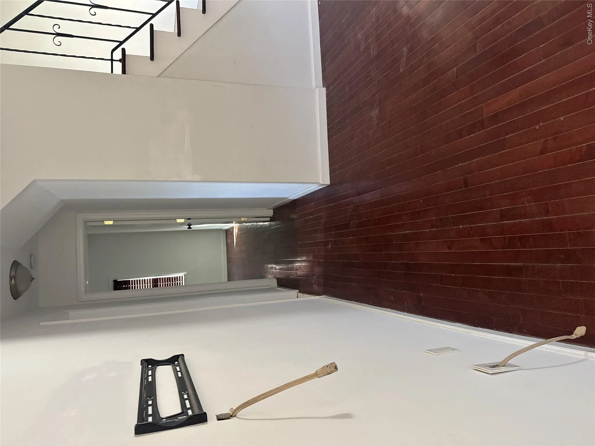 Hardwood flooring throughout, white painted walls, and a stairway with wrought iron balusters Hardwood flooring throughout, white painted walls, and a stairway with wrought iron balusters