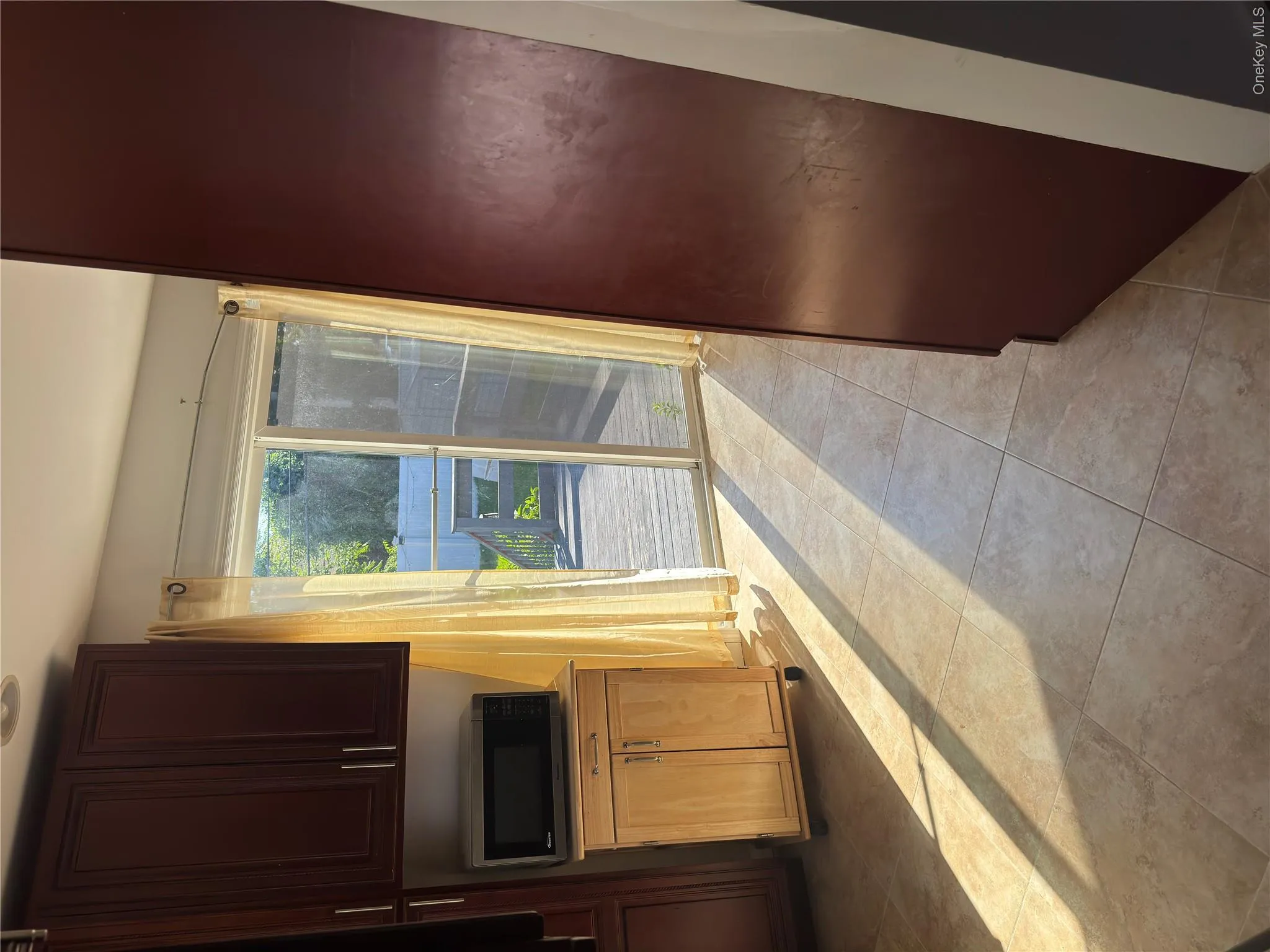 Tile flooring, dark wood-finish cabinetry, and sliding glass doors opening to a wood deck Tile flooring, dark wood-finish cabinetry, and sliding glass doors opening to a wood deck