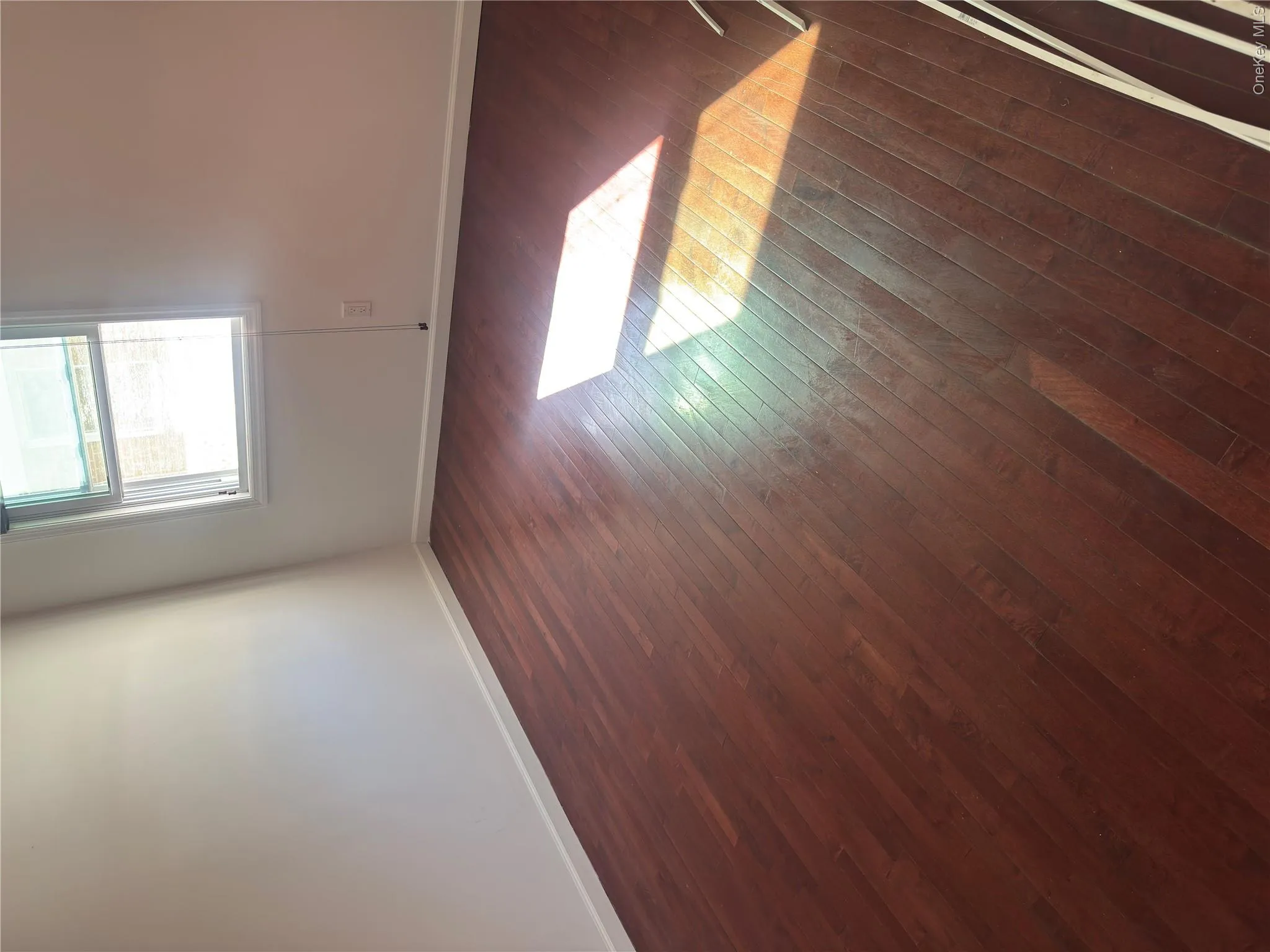Wood-finish flooring with white wall finishes and a single-pane window Wood-finish flooring with white wall finishes and a single-pane window