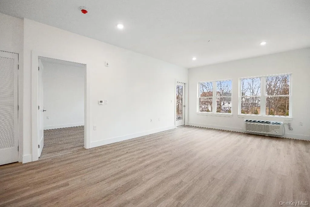 Empty room featuring light wood-type flooring and a wall unit AC Empty room featuring light wood-type flooring and a wall unit AC