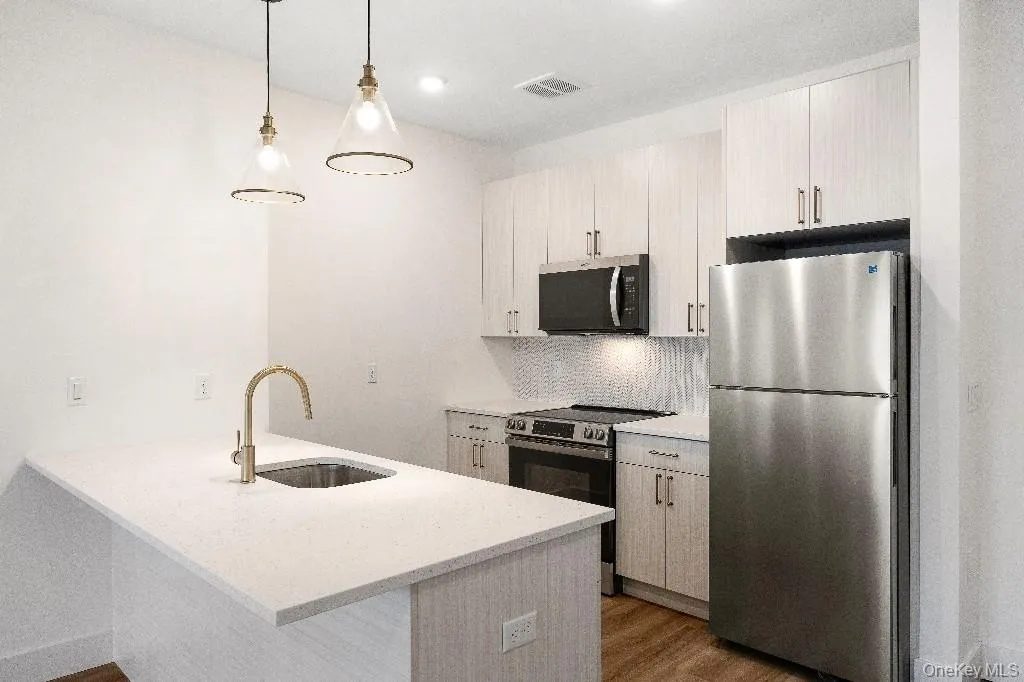 Kitchen with sink, kitchen peninsula, stainless steel appliances, and hanging light fixtures Kitchen with sink, kitchen peninsula, stainless steel appliances, and hanging light fixtures