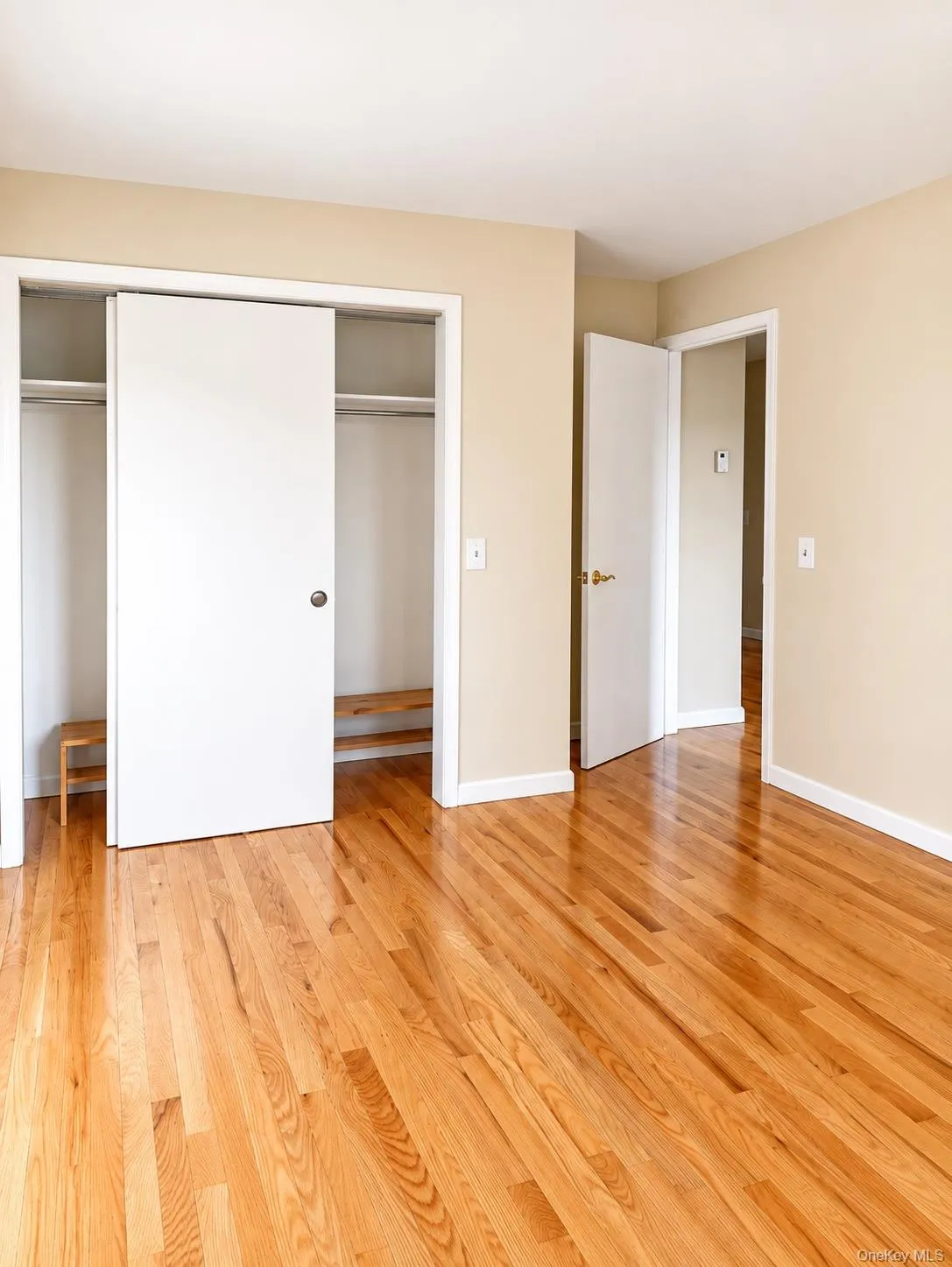 Hardwood flooring, neutral wall tones, white trim, sliding closet doors, and a built-in closet shelf Hardwood flooring, neutral wall tones, white trim, sliding closet doors, and a built-in closet shelf