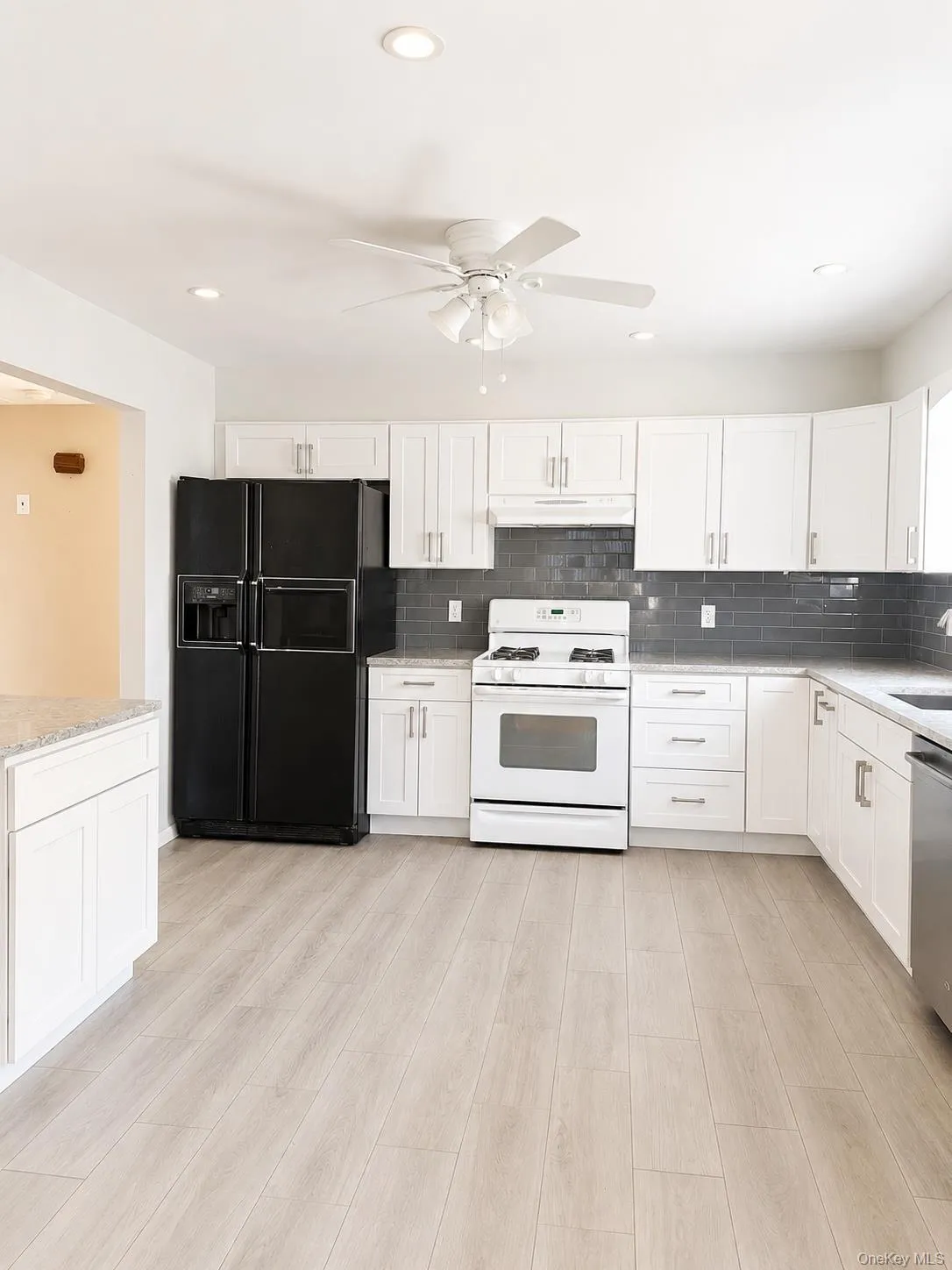 Kitchen featuring white cabinetry, light-toned wood-finish flooring, recessed lighting, and a ceiling fan Kitchen featuring white cabinetry, light-toned wood-finish flooring, recessed lighting, and a ceiling fan