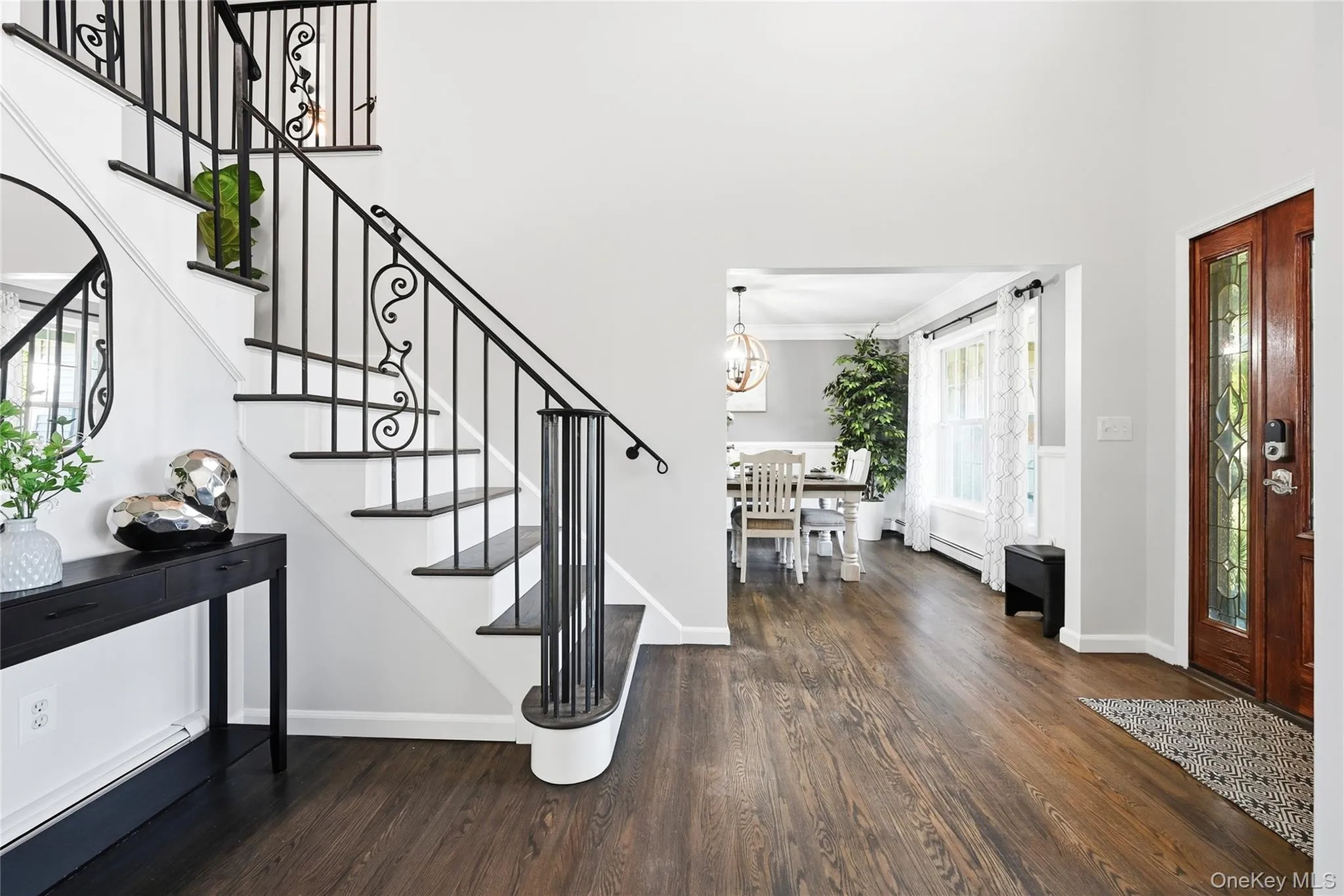 Hardwood flooring, wood-panel entry door with decorative glass, white painted walls, and an open entryway Hardwood flooring, wood-panel entry door with decorative glass, white painted walls, and an open entryway