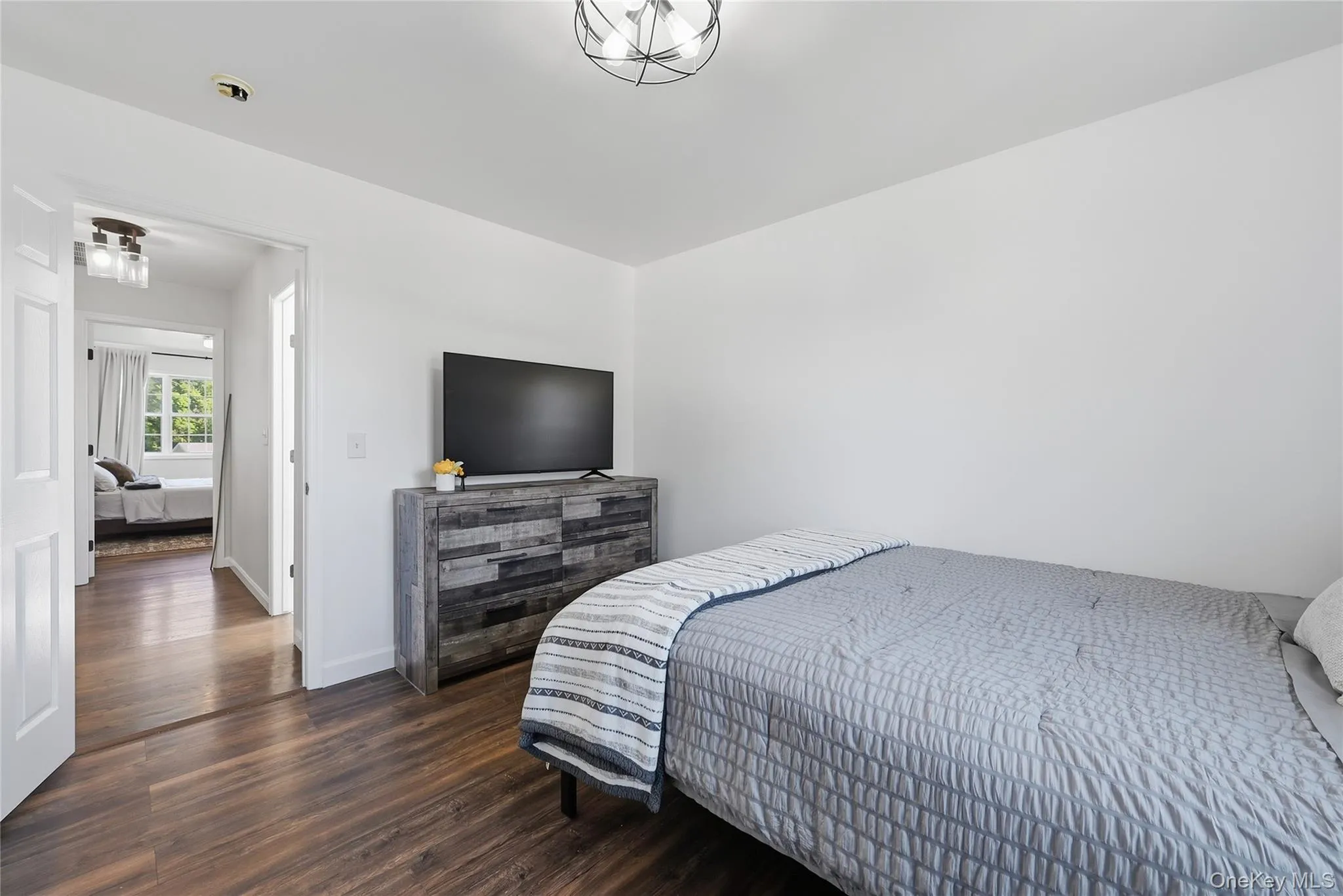 Hardwood-finish flooring throughout, white walls, and a contemporary ceiling light fixture Hardwood-finish flooring throughout, white walls, and a contemporary ceiling light fixture