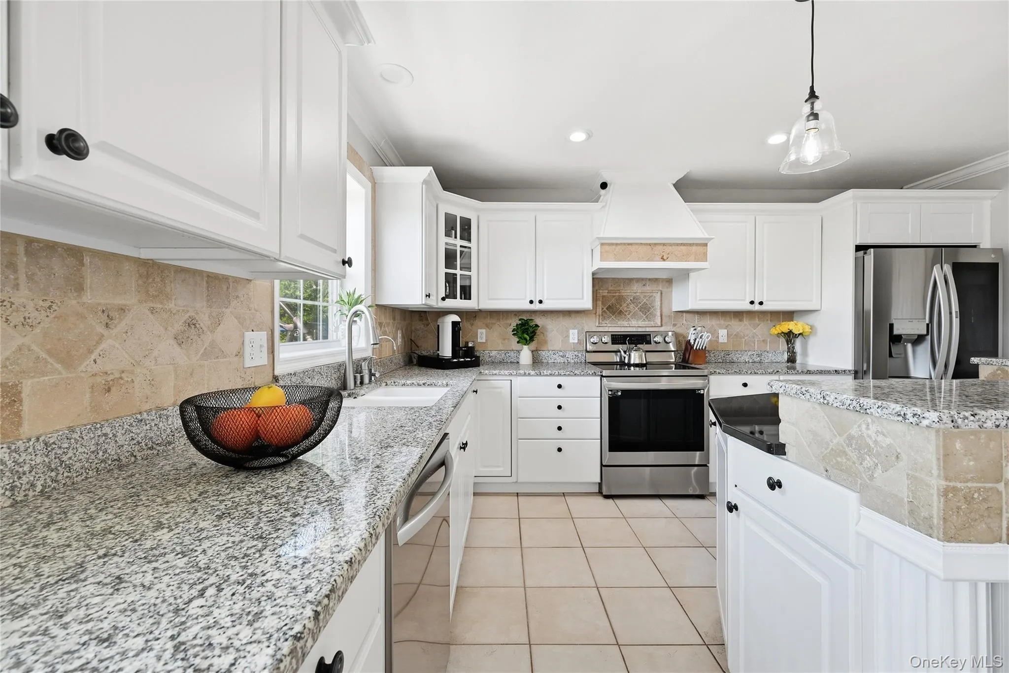 White cabinetry, granite countertops, tile backsplash, stainless steel appliances, and tile flooring White cabinetry, granite countertops, tile backsplash, stainless steel appliances, and tile flooring