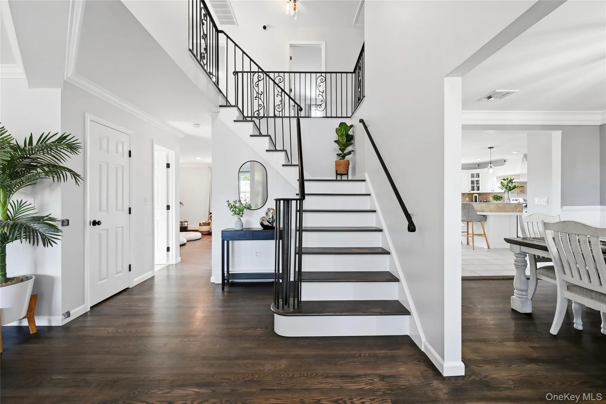 Dark wood-finish flooring, white paneled doors, black wrought iron stair railing, and crown molding Dark wood-finish flooring, white paneled doors, black wrought iron stair railing, and crown molding