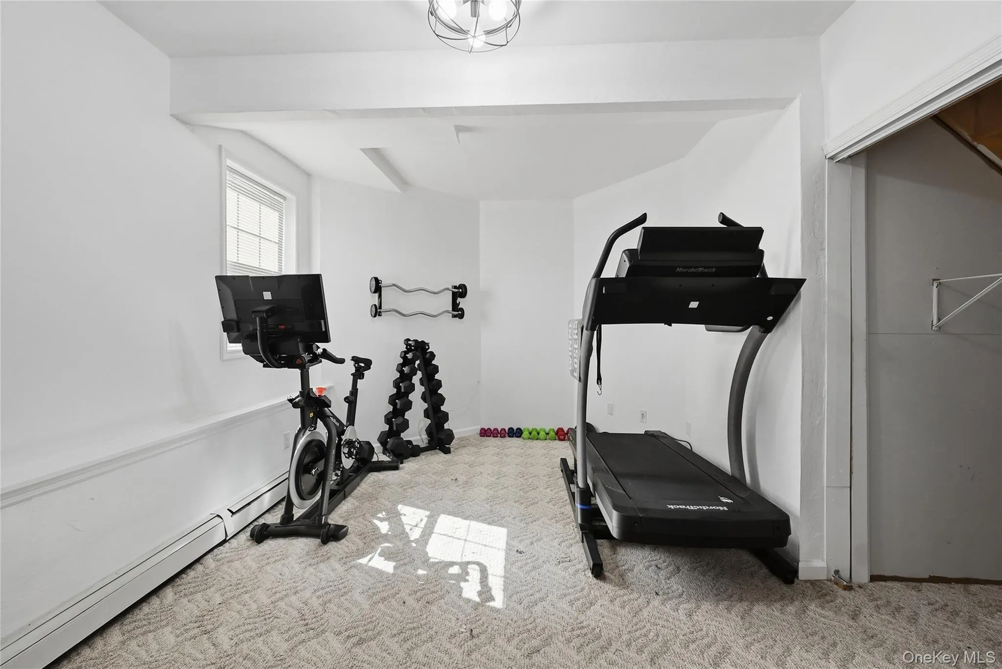 Recessed ceiling lighting, window with white trim, built-in baseboard heating, light-toned patterned carpeting, and white painted walls Recessed ceiling lighting, window with white trim, built-in baseboard heating, light-toned patterned carpeting, and white painted walls