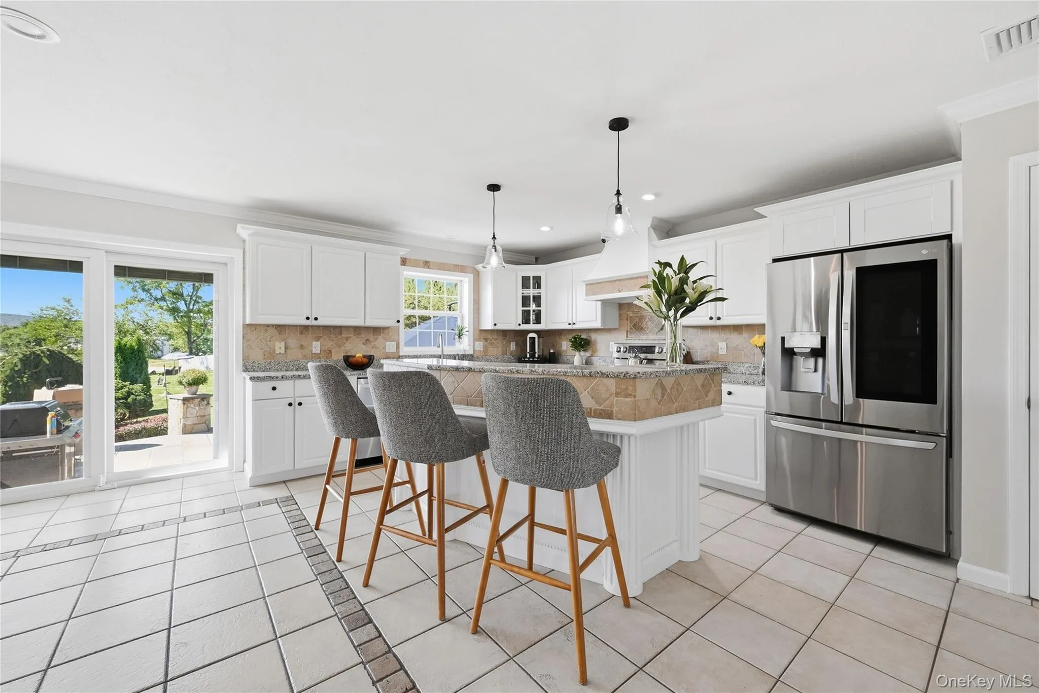 White shaker cabinetry, stainless steel refrigerator, tile flooring with decorative inlay, stone countertops, and a full-height tile backsplash White shaker cabinetry, stainless steel refrigerator, tile flooring with decorative inlay, stone countertops, and a full-height tile backsplash