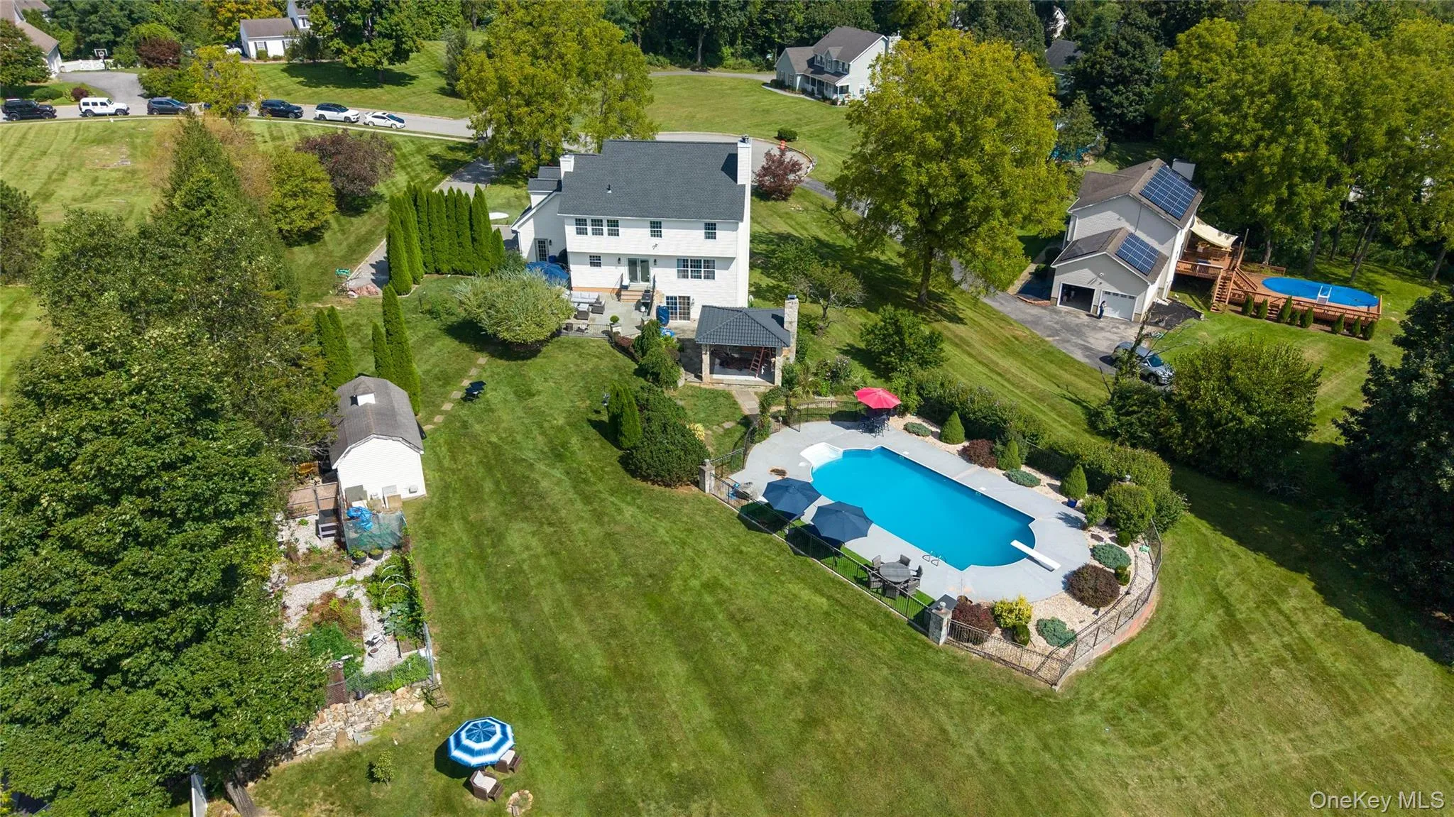 Expansive landscaped grounds with an in-ground swimming pool, adjacent covered patio, and a detached shed Expansive landscaped grounds with an in-ground swimming pool, adjacent covered patio, and a detached shed