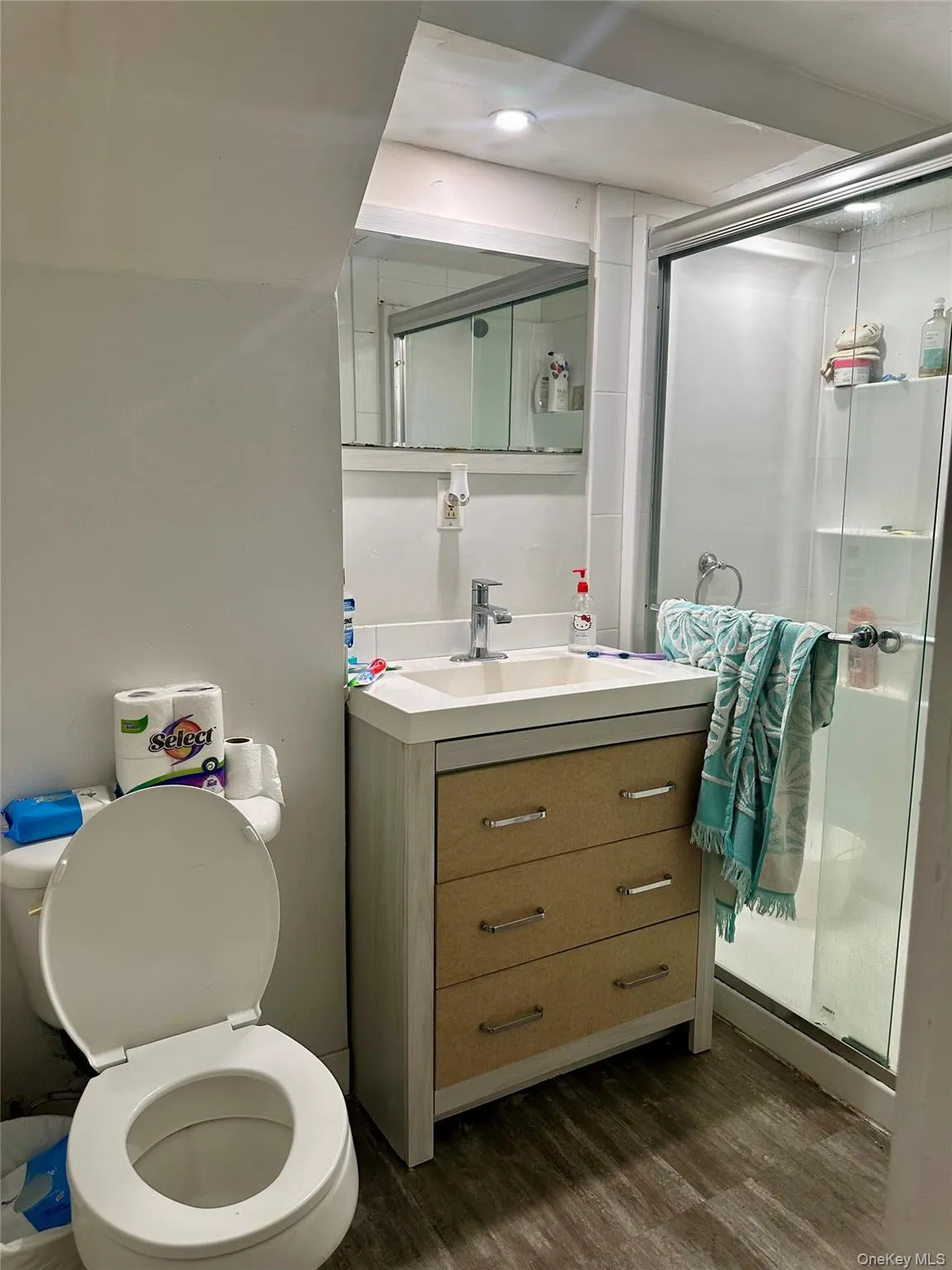 Bathroom featuring a stall shower, vanity, toilet, and wood finished floors Bathroom featuring a stall shower, vanity, toilet, and wood finished floors