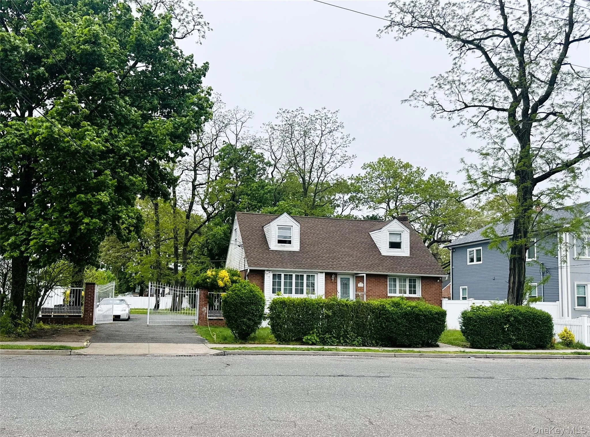 New england style home with fence, a chimney, and brick siding New england style home with fence, a chimney, and brick siding