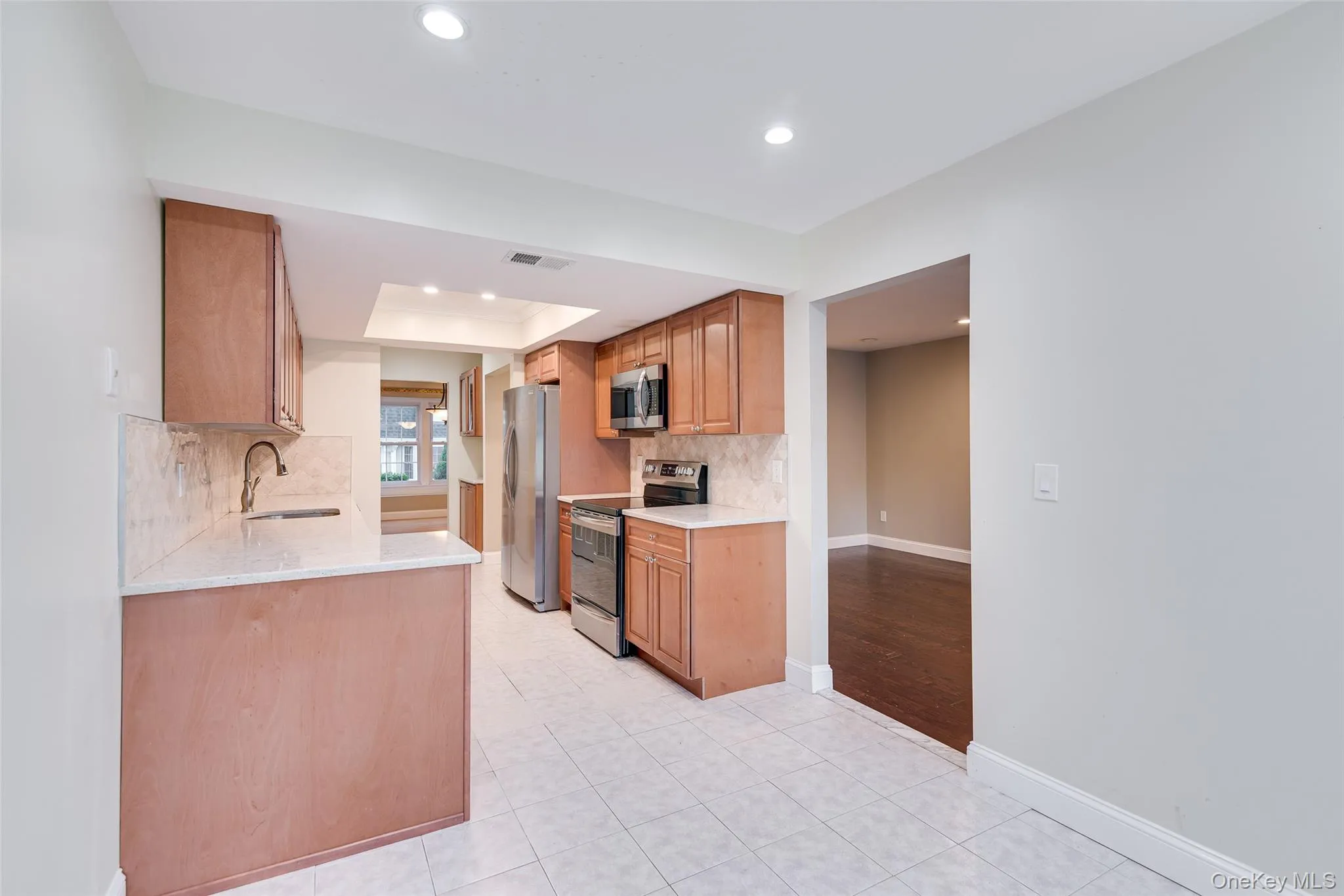 Kitchen featuring wood cabinetry, stainless steel appliances, recessed lighting, and tile flooring Kitchen featuring wood cabinetry, stainless steel appliances, recessed lighting, and tile flooring