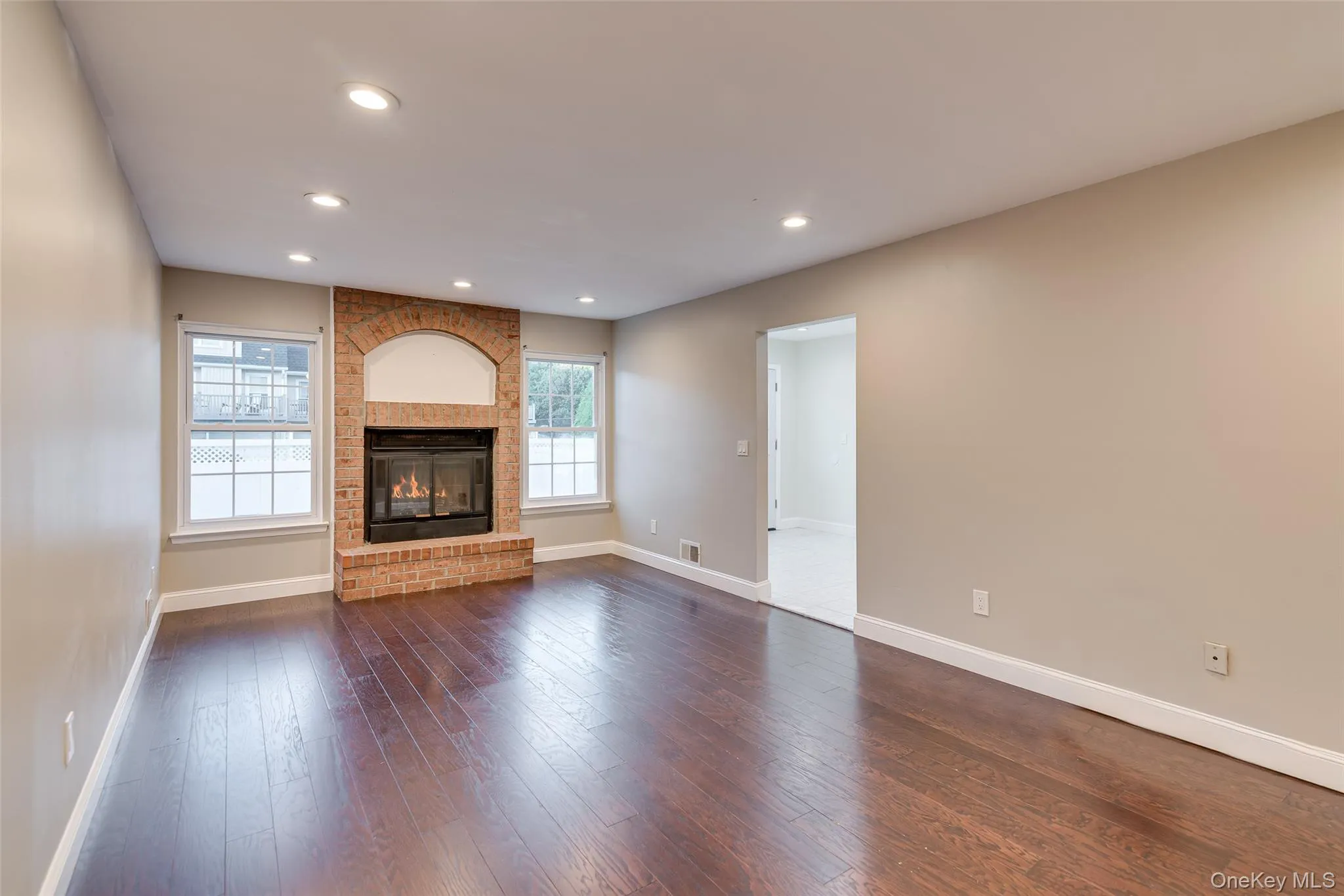 Brick fireplace with an arched alcove, dark wood-finish flooring, recessed lighting, and bright white trim Brick fireplace with an arched alcove, dark wood-finish flooring, recessed lighting, and bright white trim
