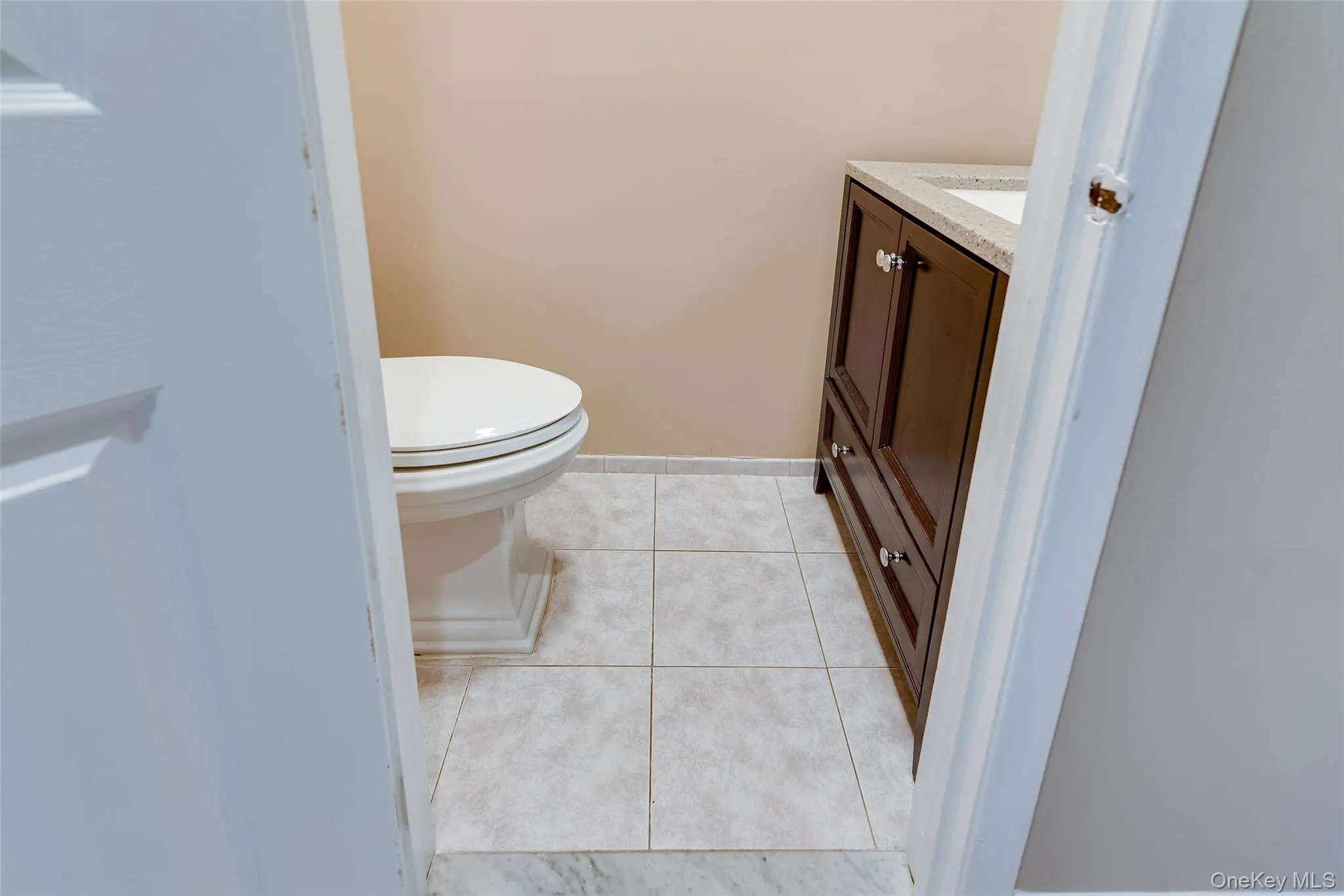 Tile flooring with a dark wood-finish vanity and integrated sink Tile flooring with a dark wood-finish vanity and integrated sink