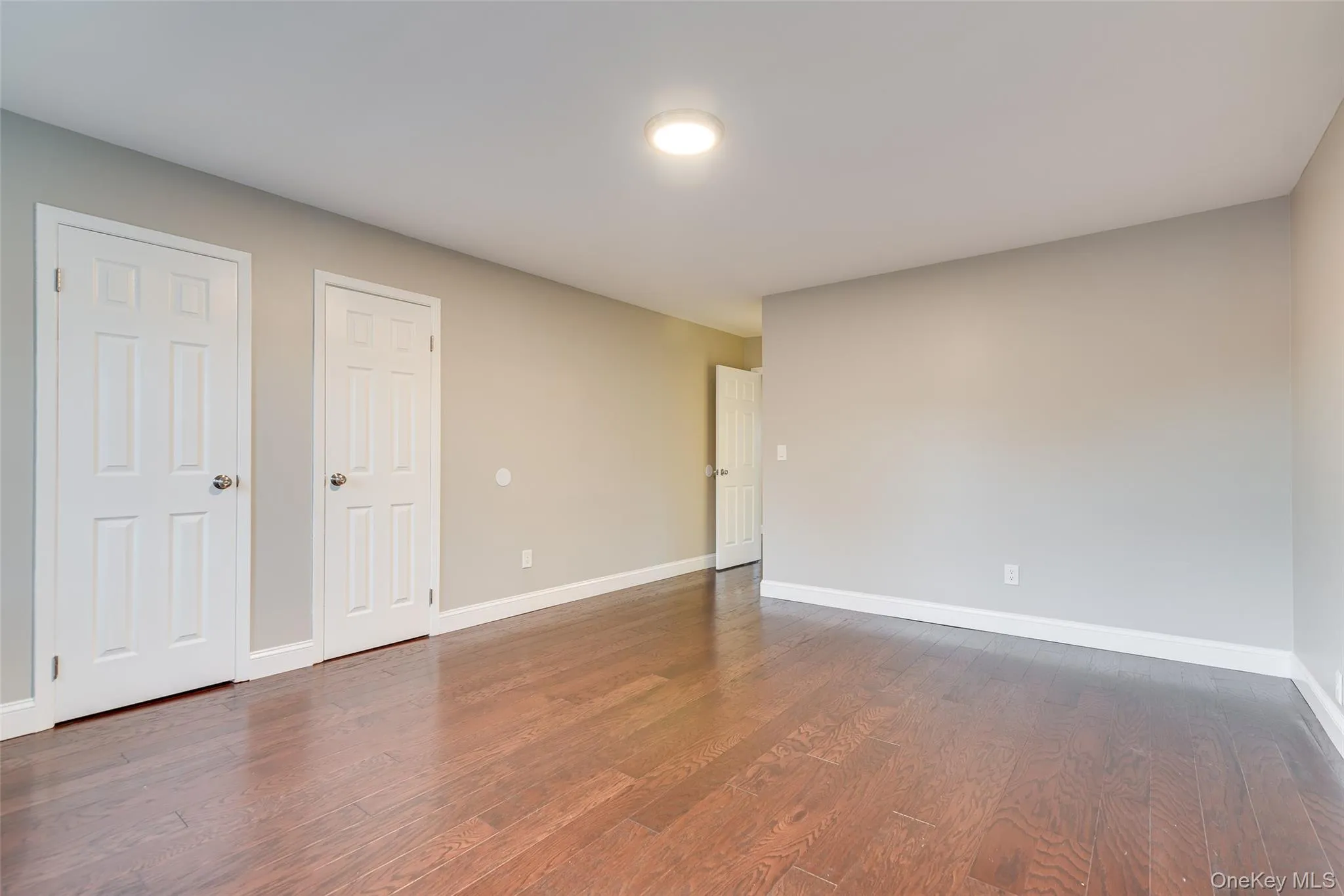Wood-finish flooring, light gray wall paint, white trim, recessed lighting, and white six-panel doors Wood-finish flooring, light gray wall paint, white trim, recessed lighting, and white six-panel doors