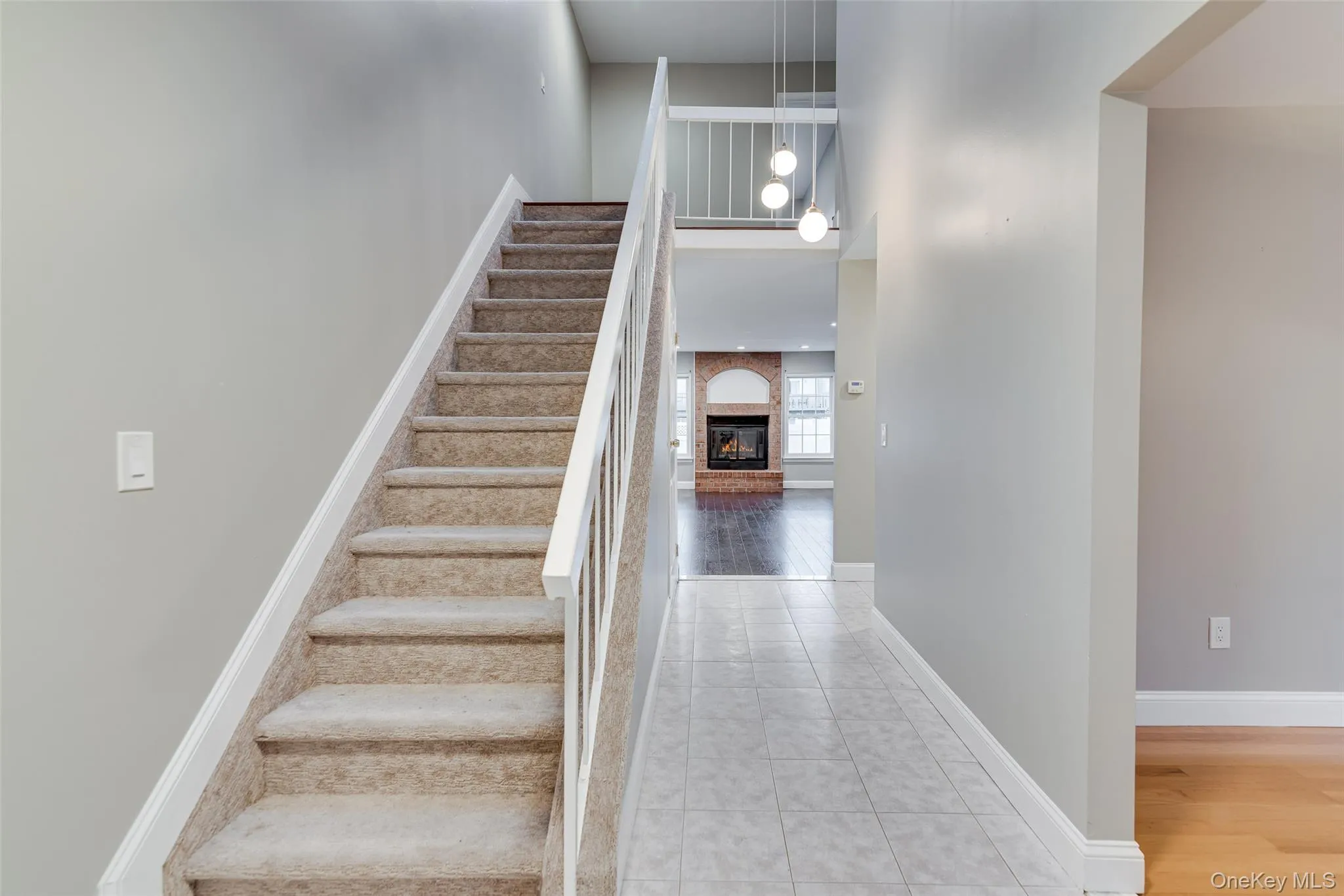 Carpeted staircase with white railings, a tiled entryway, and recessed lighting Carpeted staircase with white railings, a tiled entryway, and recessed lighting