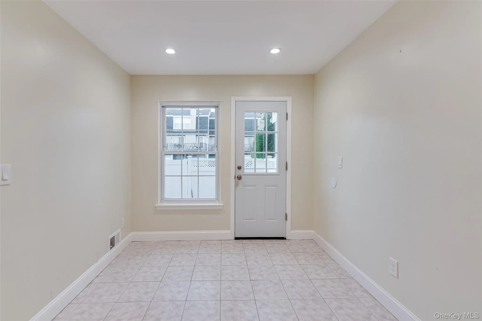 Light-toned tile flooring, recessed lighting, and a white paneled door with glass inserts Light-toned tile flooring, recessed lighting, and a white paneled door with glass inserts