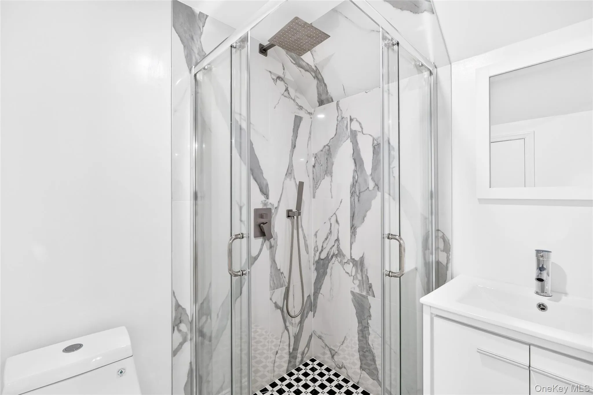 Corner shower with glass enclosure, rain shower head, handheld shower, and patterned floor tile Corner shower with glass enclosure, rain shower head, handheld shower, and patterned floor tile