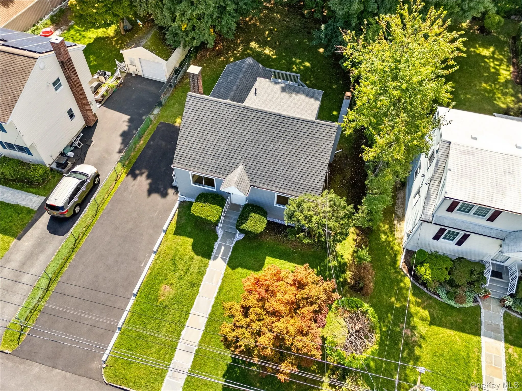 Gable roof with asphalt shingles, light-colored siding, concrete walkway, and a paved driveway Gable roof with asphalt shingles, light-colored siding, concrete walkway, and a paved driveway