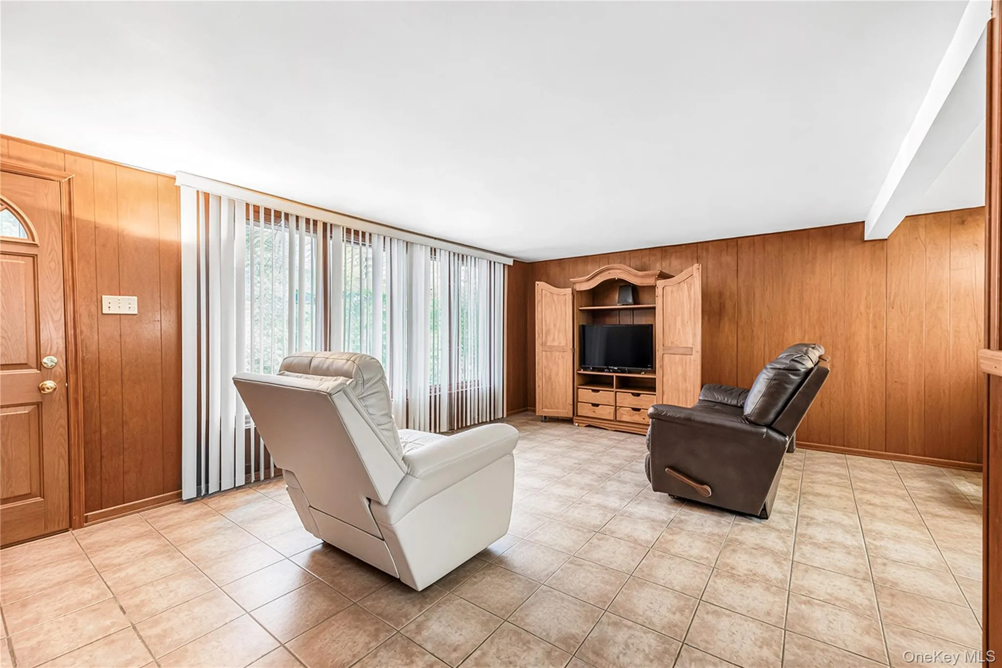 Tiled flooring, wood paneling, built-in media cabinetry, and a pass-through opening Tiled flooring, wood paneling, built-in media cabinetry, and a pass-through opening