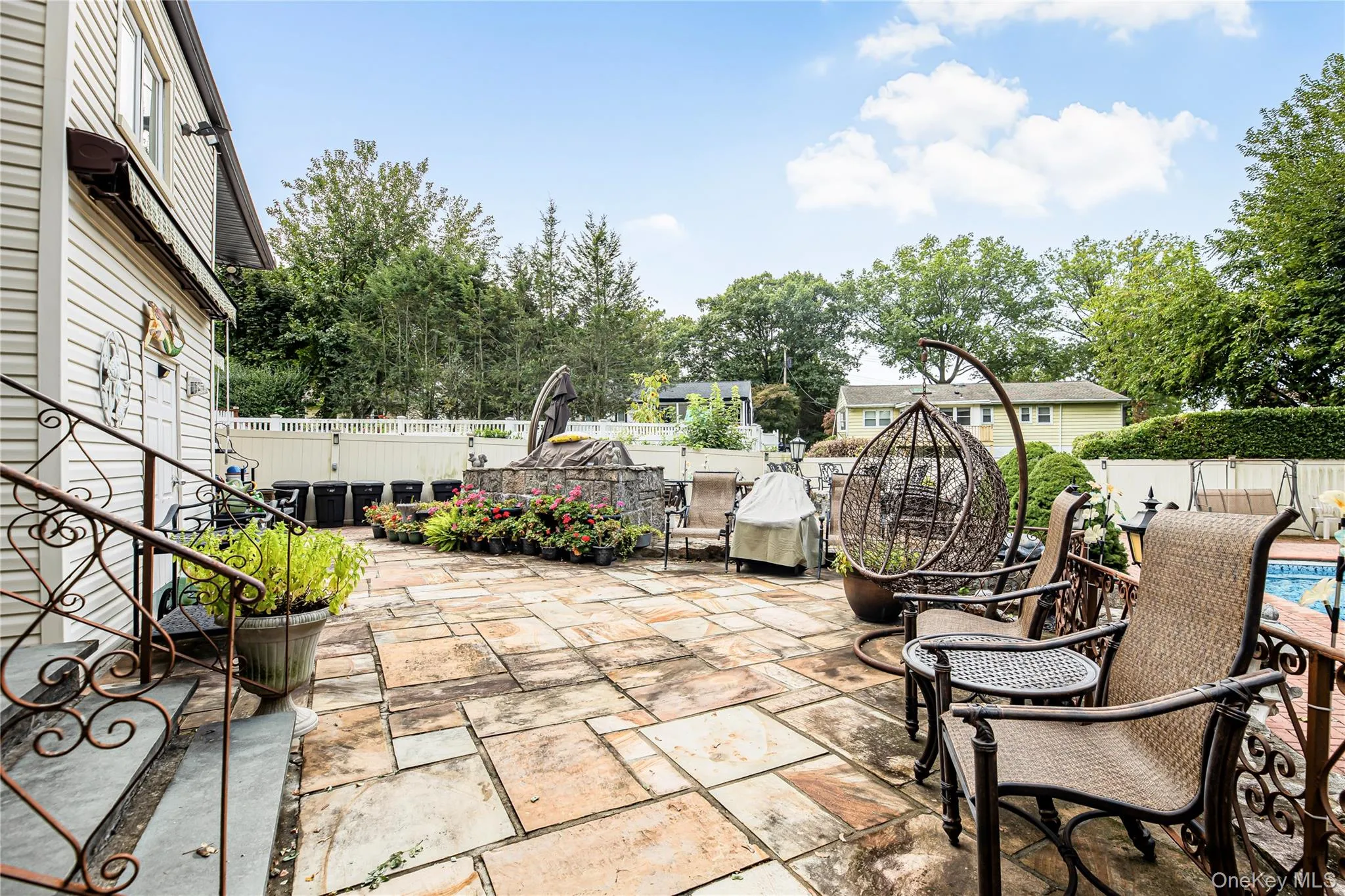 Expansive stone patio featuring a stone-faced raised planter and white privacy fencing Expansive stone patio featuring a stone-faced raised planter and white privacy fencing