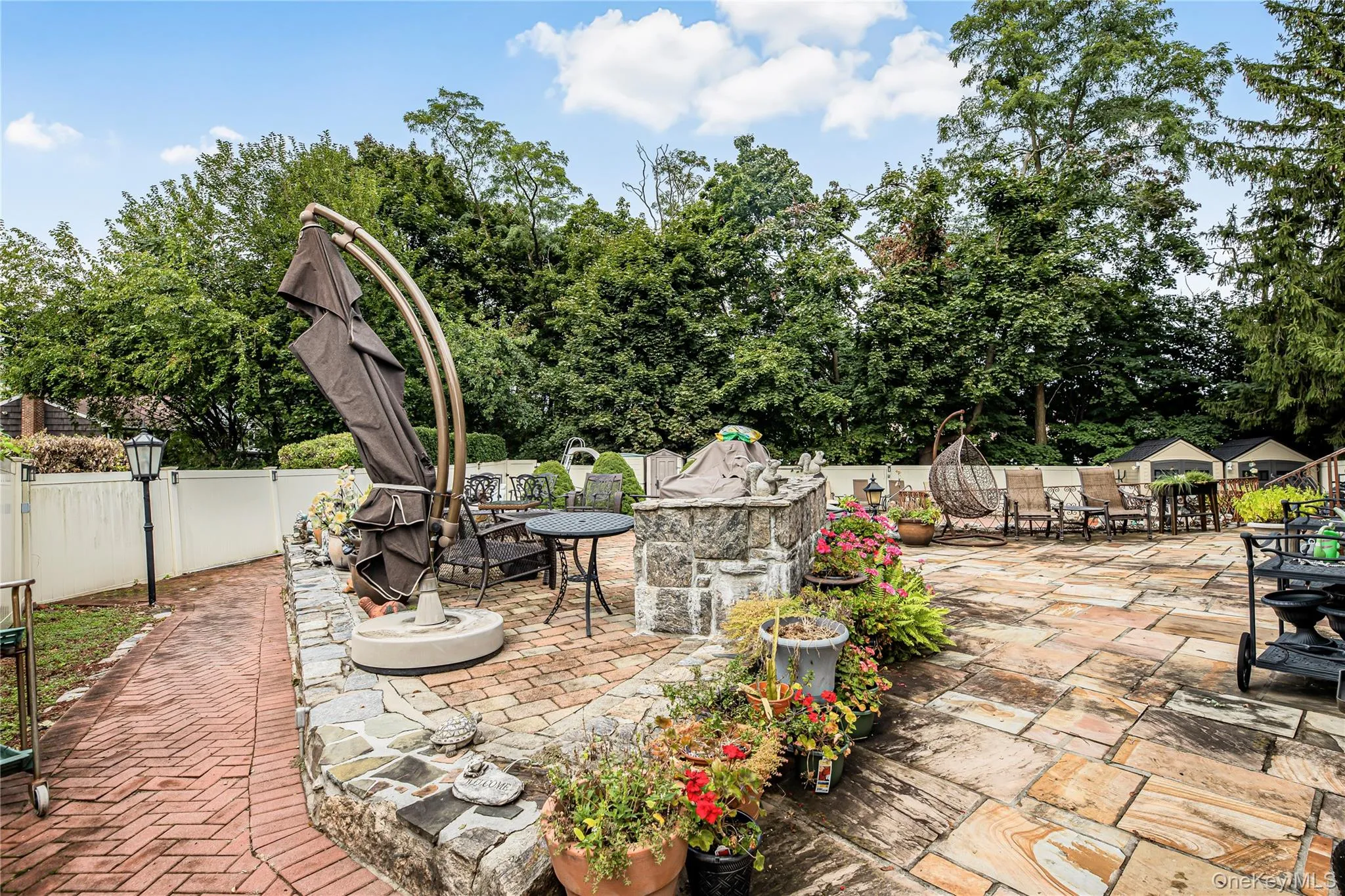 Expansive patio featuring flagstone paving, a stone-faced retaining wall, and a brick pathway Expansive patio featuring flagstone paving, a stone-faced retaining wall, and a brick pathway
