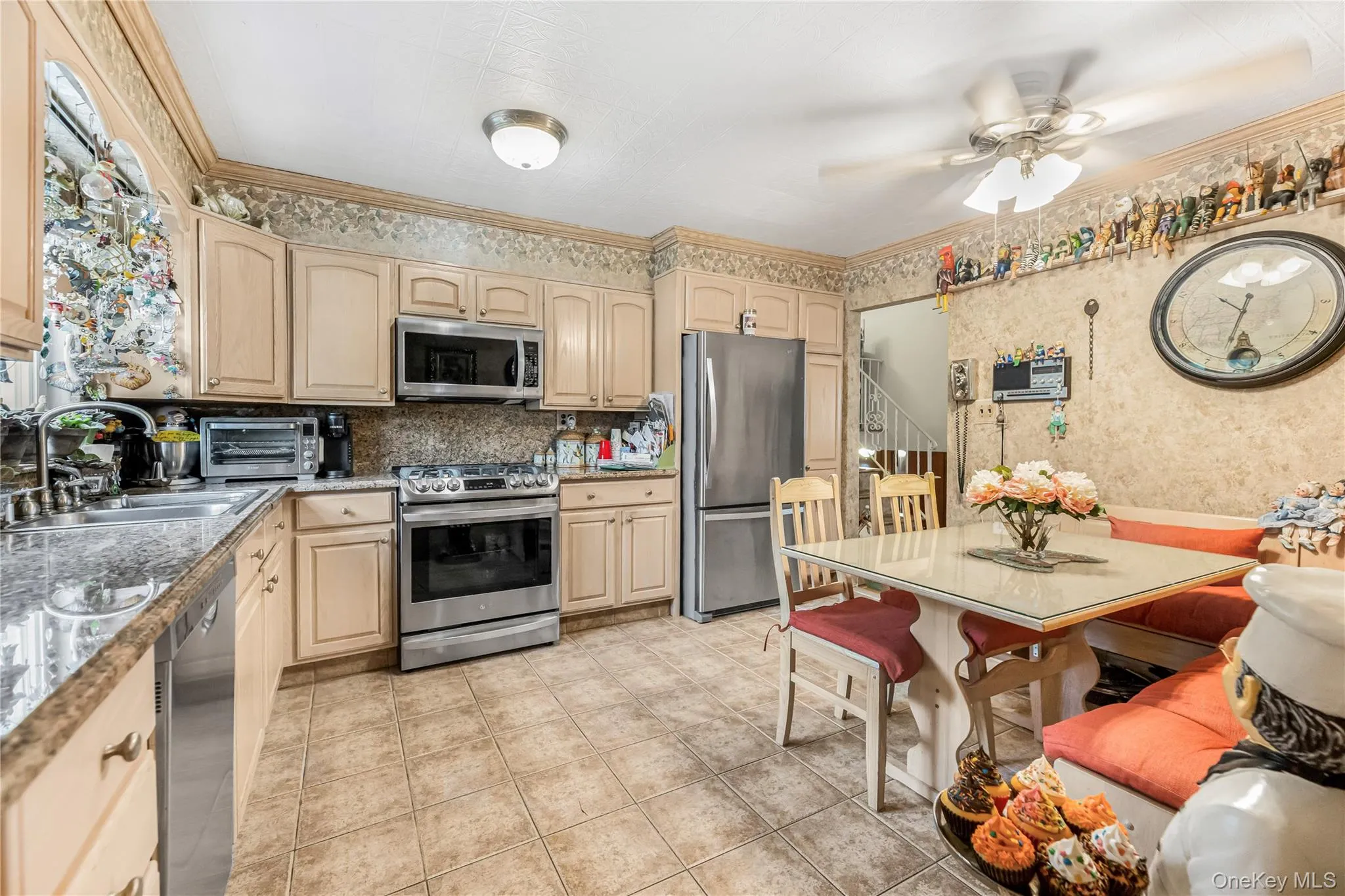Kitchen featuring light-toned cabinetry, tile flooring, and stainless steel appliances Kitchen featuring light-toned cabinetry, tile flooring, and stainless steel appliances