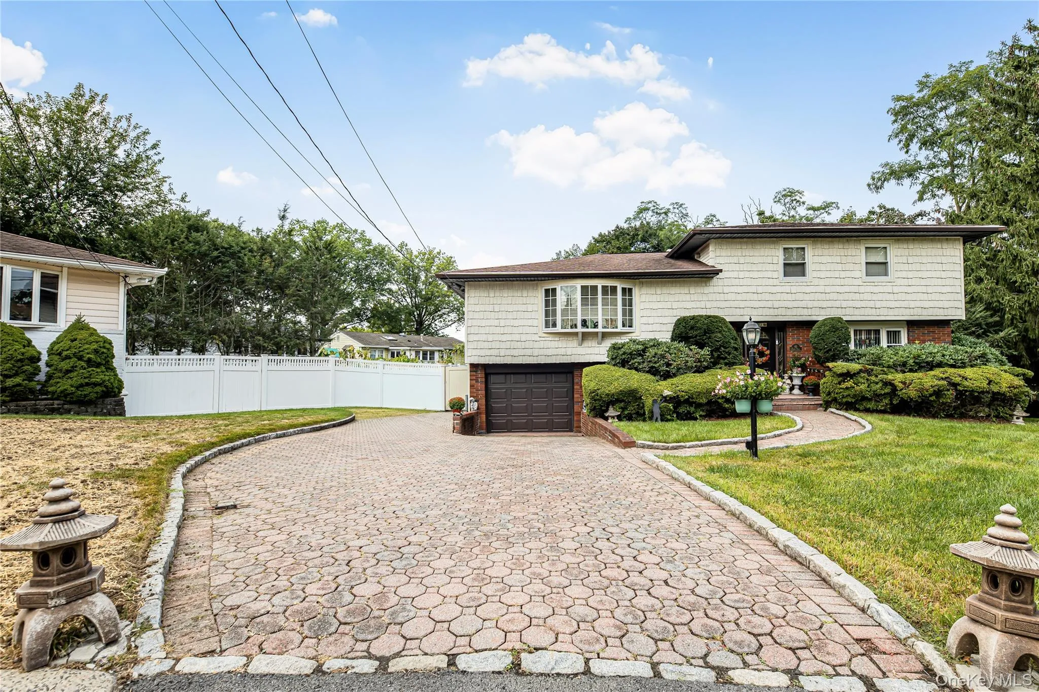 Split-level residence featuring a bay window, attached garage, and a paver driveway Split-level residence featuring a bay window, attached garage, and a paver driveway