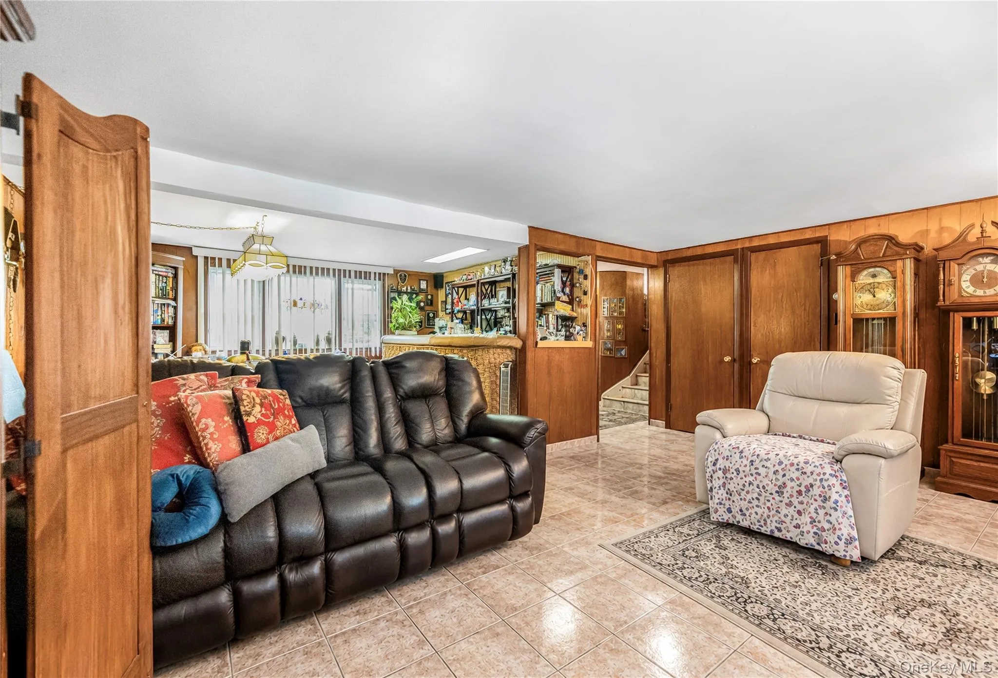Tiled flooring, wood paneling, built-in media cabinetry, and a pass-through opening Tiled flooring, wood paneling, built-in media cabinetry, and a pass-through opening