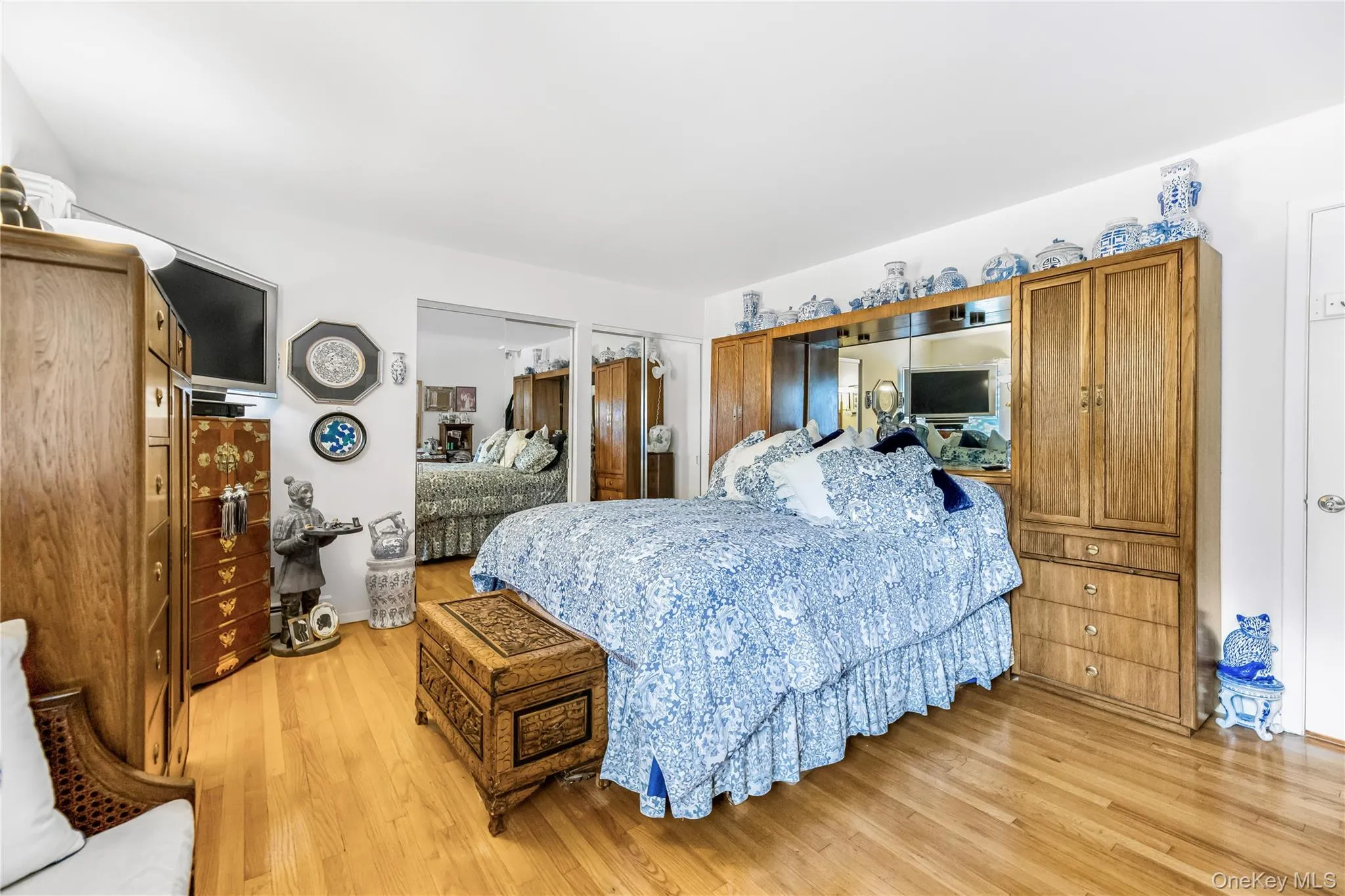 Hardwood flooring, built-in mirrored cabinetry, sliding mirrored closet doors, recessed lighting, and a white paneled door Hardwood flooring, built-in mirrored cabinetry, sliding mirrored closet doors, recessed lighting, and a white paneled door