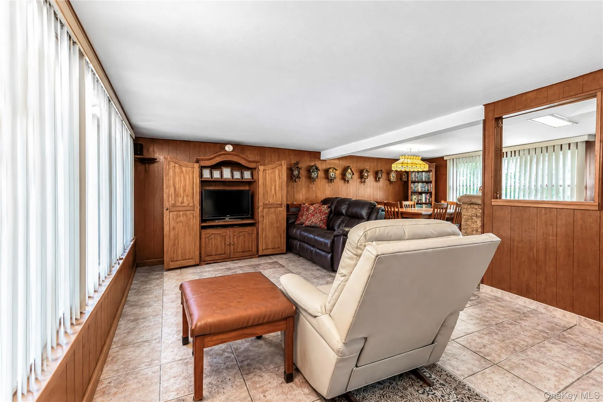 Tiled flooring, wood paneling, built-in media cabinetry, and a pass-through opening Tiled flooring, wood paneling, built-in media cabinetry, and a pass-through opening