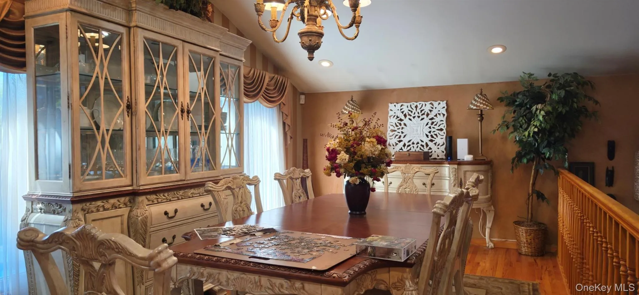 Vaulted ceiling with recessed lighting and a chandelier, wood-finish flooring, and ornate millwork on cabinetry Vaulted ceiling with recessed lighting and a chandelier, wood-finish flooring, and ornate millwork on cabinetry
