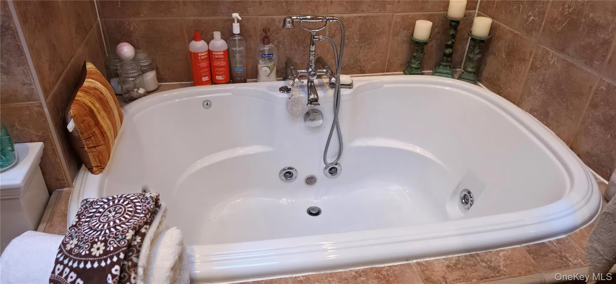 Integrated soaking tub with chrome fixtures and tiled surround Integrated soaking tub with chrome fixtures and tiled surround