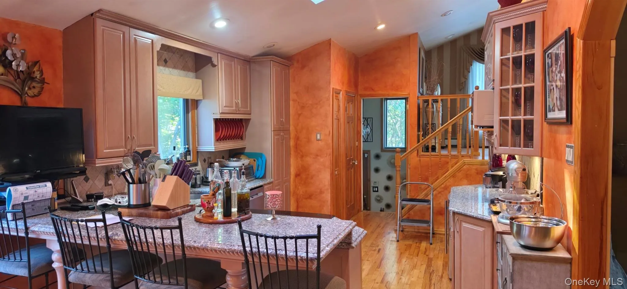 Kitchen featuring light-toned cabinetry, a granite-finish island with seating, recessed lighting, and wood-finish flooring Kitchen featuring light-toned cabinetry, a granite-finish island with seating, recessed lighting, and wood-finish flooring