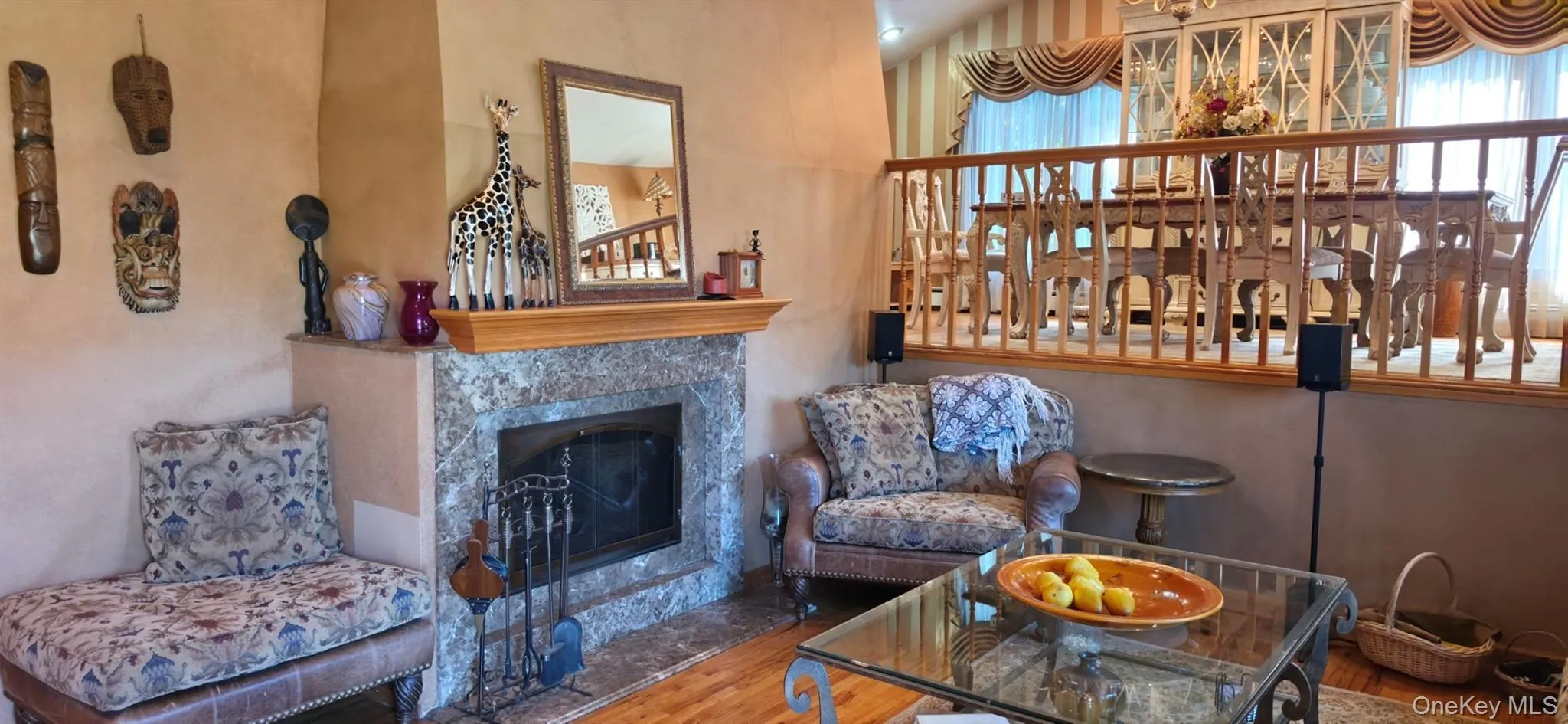Stone-surround fireplace with a wood mantle, wood-finish flooring, and a decorative railing Stone-surround fireplace with a wood mantle, wood-finish flooring, and a decorative railing