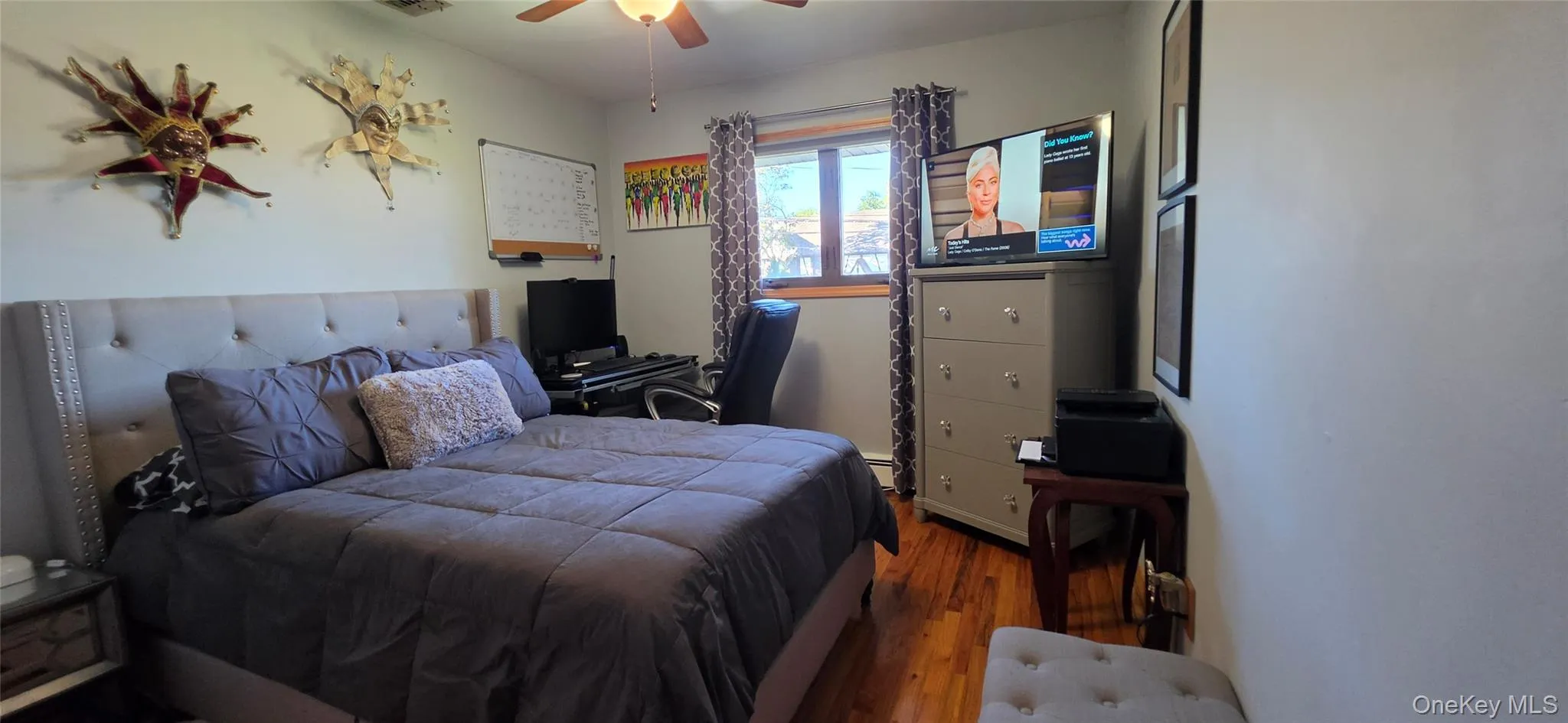 Wood-finish flooring, central ceiling fan with integrated light fixture, and a window with wood-trim casing Wood-finish flooring, central ceiling fan with integrated light fixture, and a window with wood-trim casing
