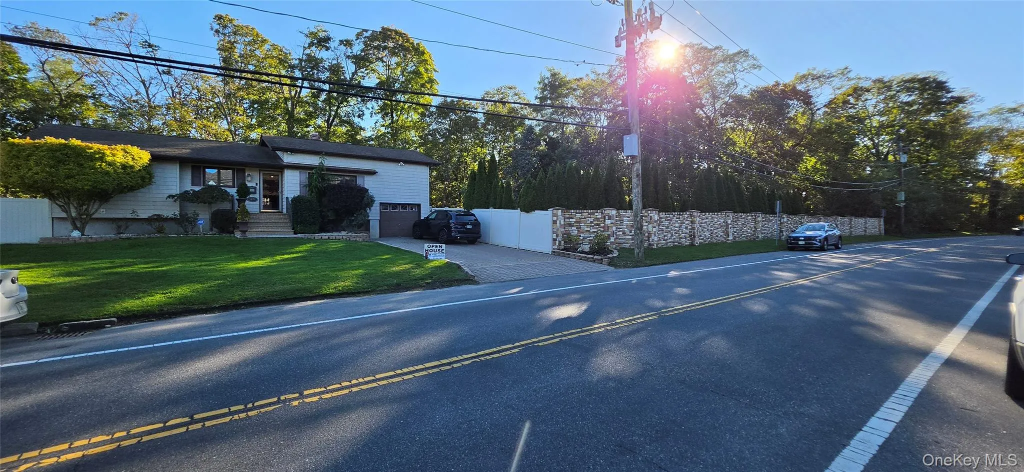 Split-level exterior featuring horizontal siding, a paved driveway, stone-veneer wall section, and manicured lawn Split-level exterior featuring horizontal siding, a paved driveway, stone-veneer wall section, and manicured lawn
